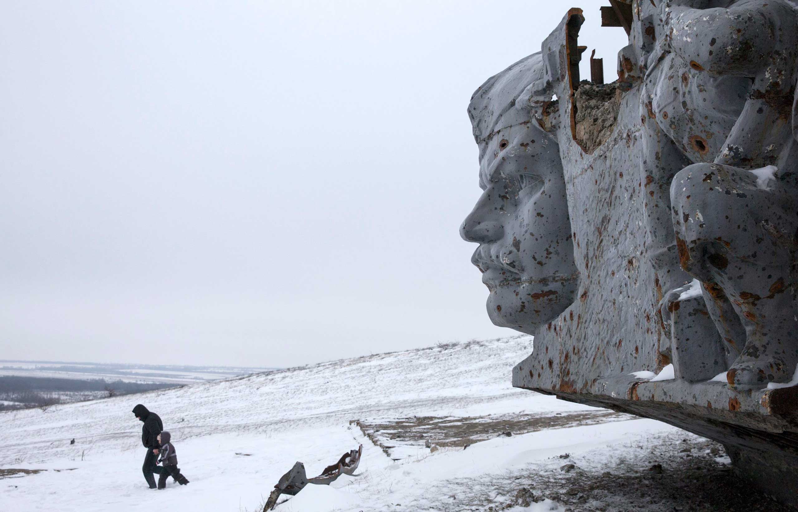 Dec. 7, 2014. A man and a child walk in the snow near the World War II memorial of the fallen Red Army soldiers at Savur-Mohyla, a hill east of the city of Donetsk. The memorial was destroyed after enduring heavy shelling during the conflict between the Ukraine Army and pro-Russian rebels.
