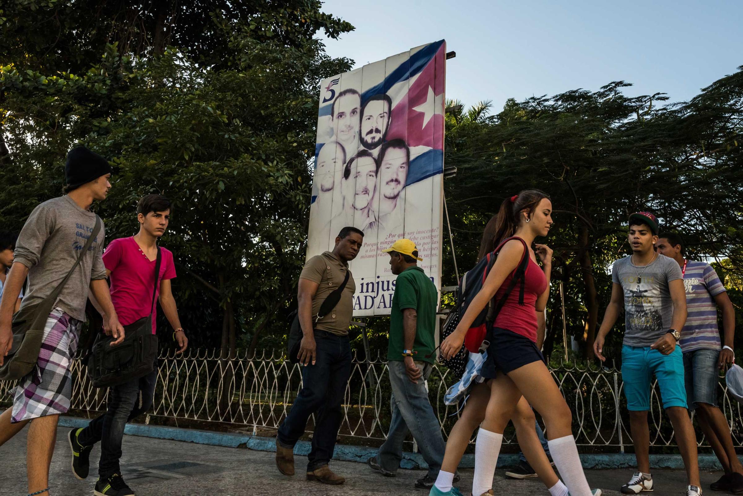 People pass a poster calling for the release of the Cuban Five spies, the last of who were released on Wednesday, in Havana.