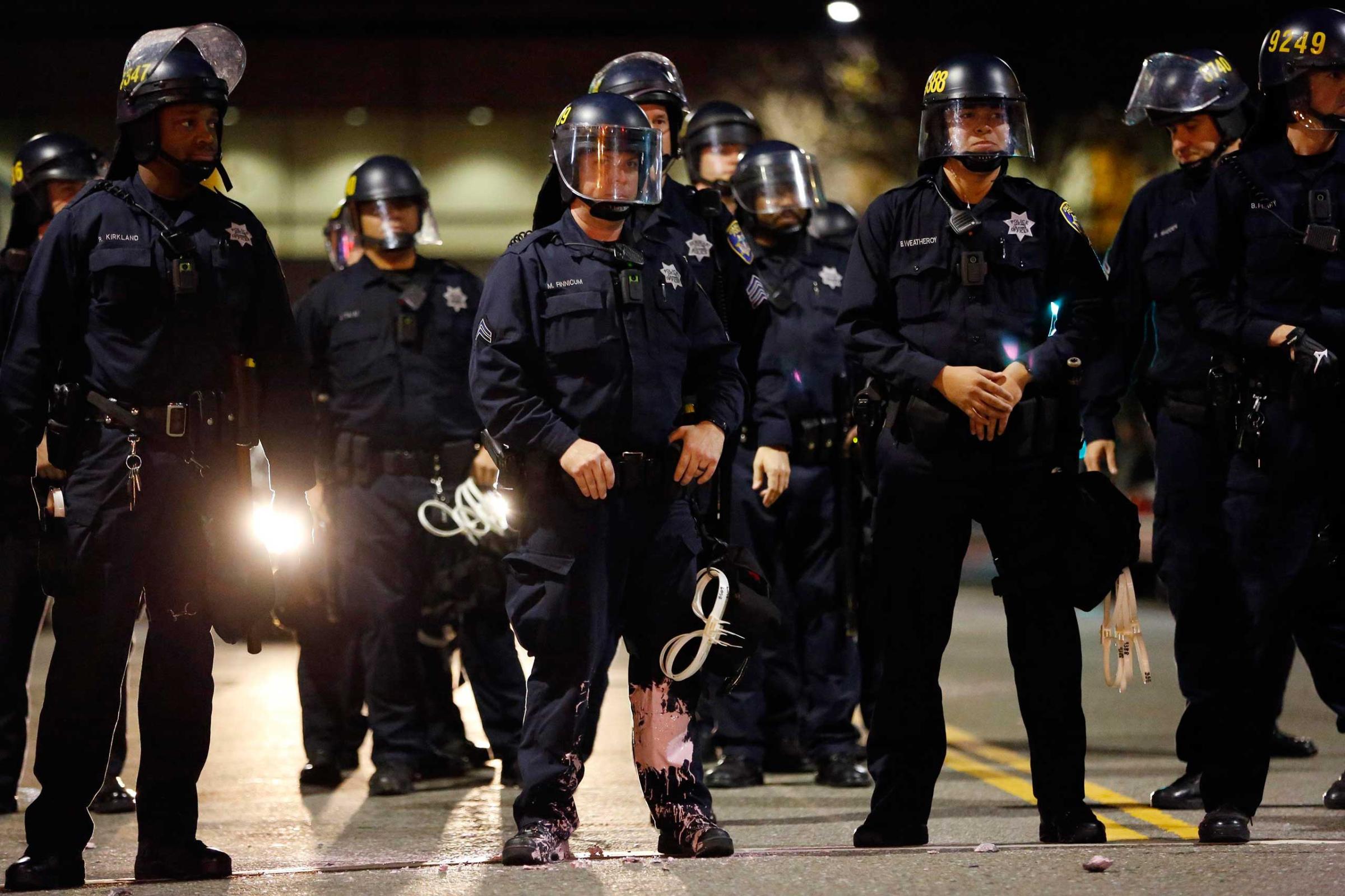 A police officer looks into the crowd, after he was hit on the leg with paint thrown by protesters, in Oakland