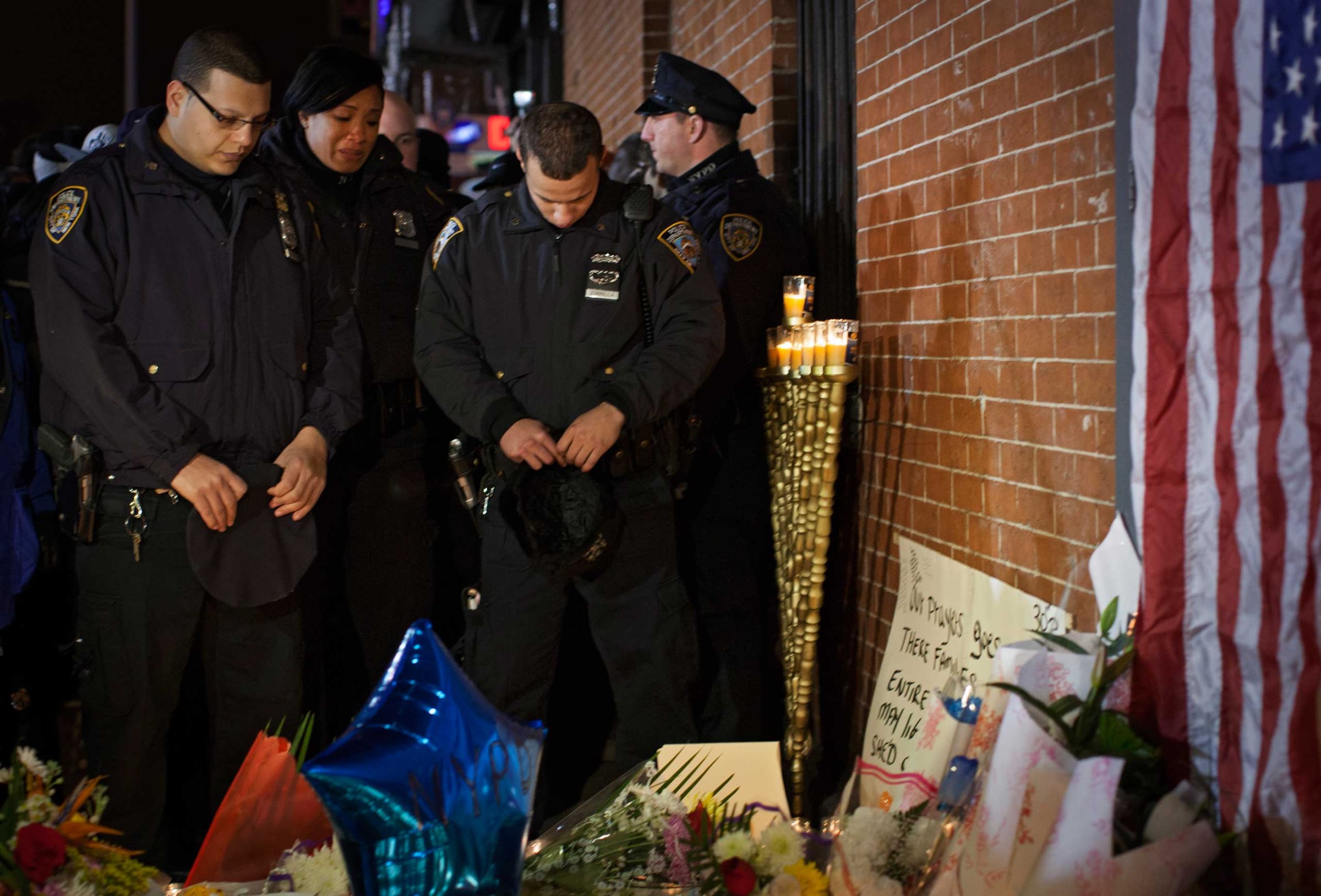 Police officers pause in front of a memorial for two police officers who were killed in Brooklyn on Dec. 21, 2014.