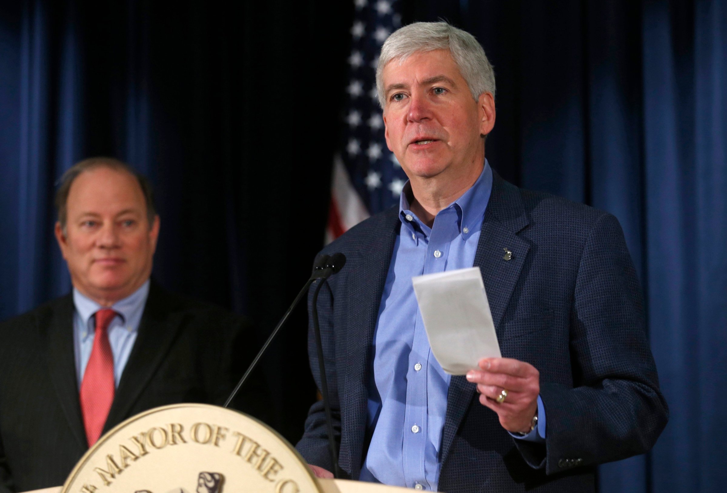 Michigan Governor Rick Snyder holds a rebate check for $1.2 million dollars to hand to Detroit Mayor Mike Duggan during a news conference discussing the city of Detroit exiting from bankruptcy in Detroit