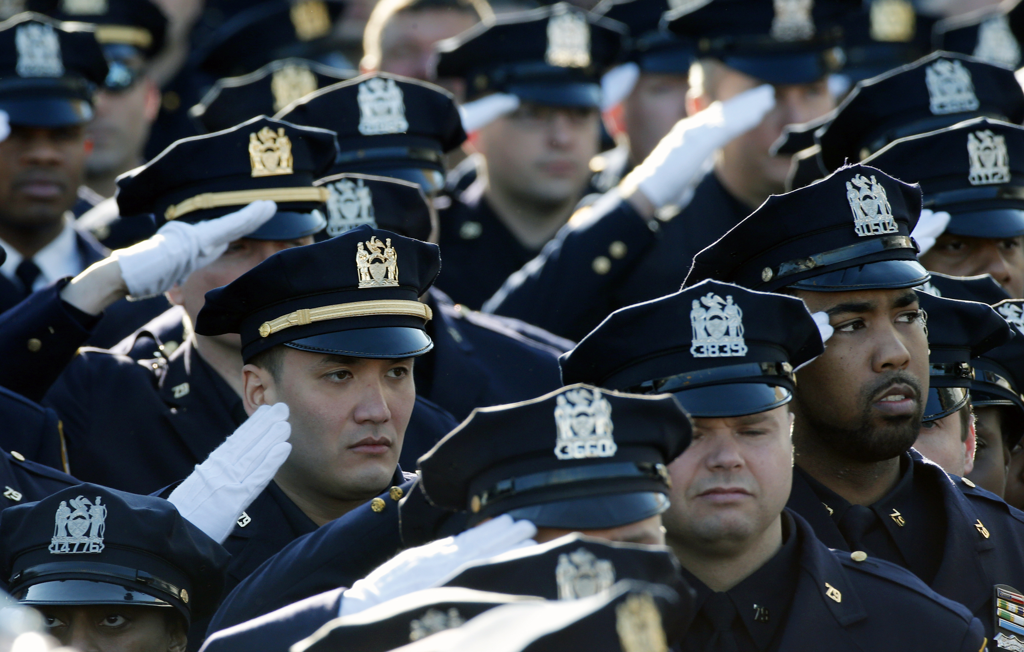 Police salute during the playing of the U.S. national anthem outside the Christ Tabernacle Church in New York City at the start of the funeral service for slain New York Police Department officer Rafael Ramos on Dec. 27, 2014 (© Mike Segar— Reuters)