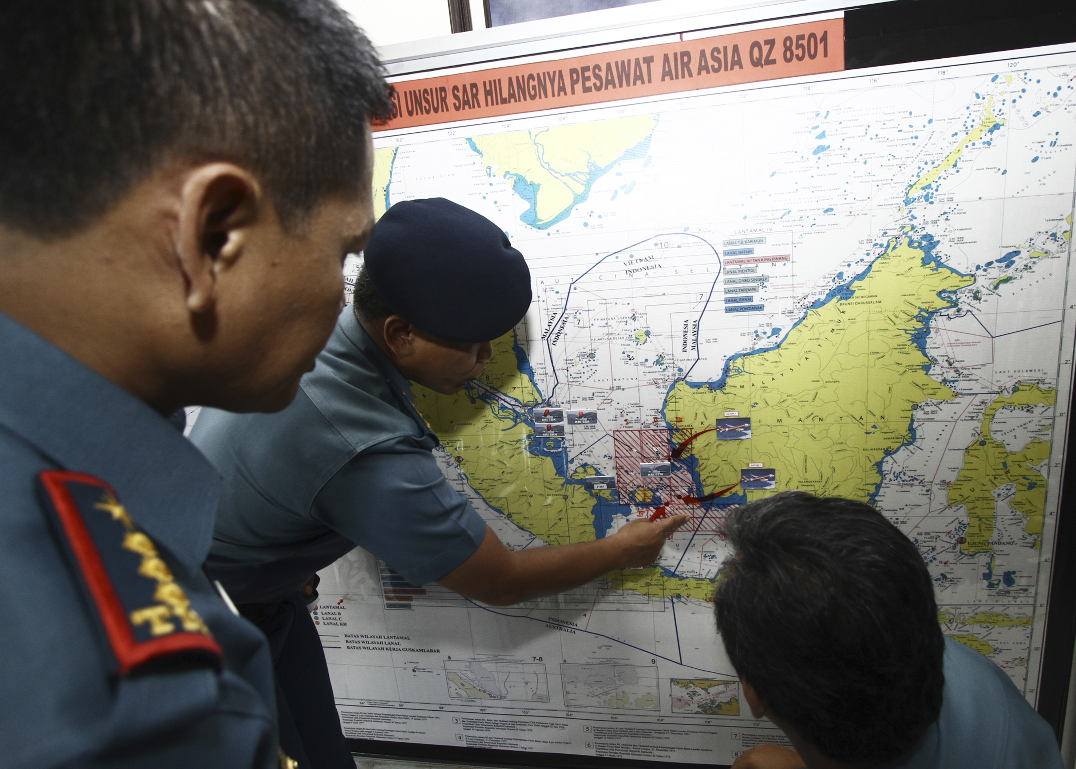 Navy soldiers work on a map of Indonesia monitoring all Navy ships from Indonesia, Singapore, and Malaysia involved in the joint search and rescue operation for AirAsia flight QZ8501 at a navy base on Batam island
