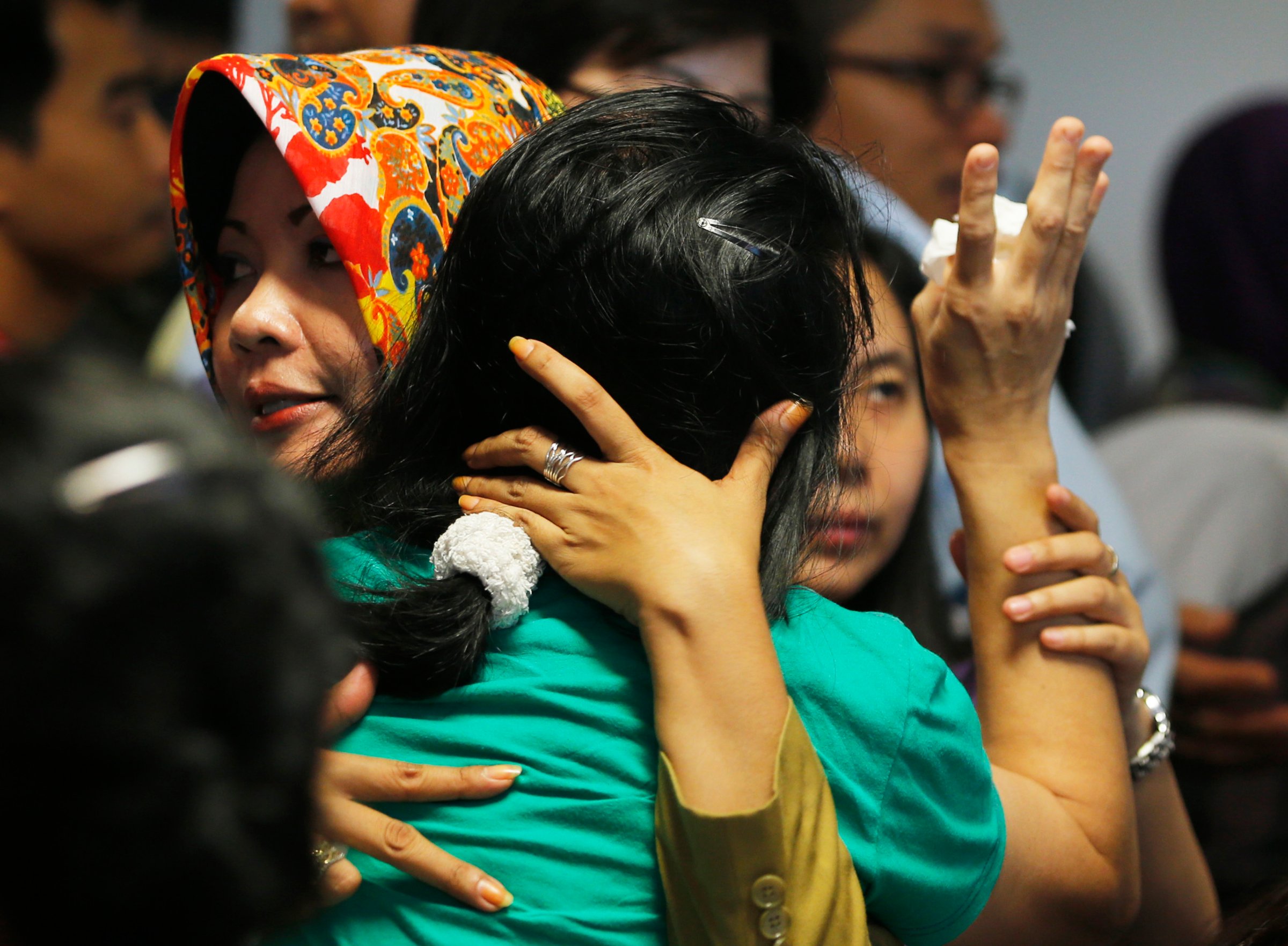 Government official tries to calm a family member of passengers onboard AirAsia flight QZ8501 at a waiting area in Juanda International Airport