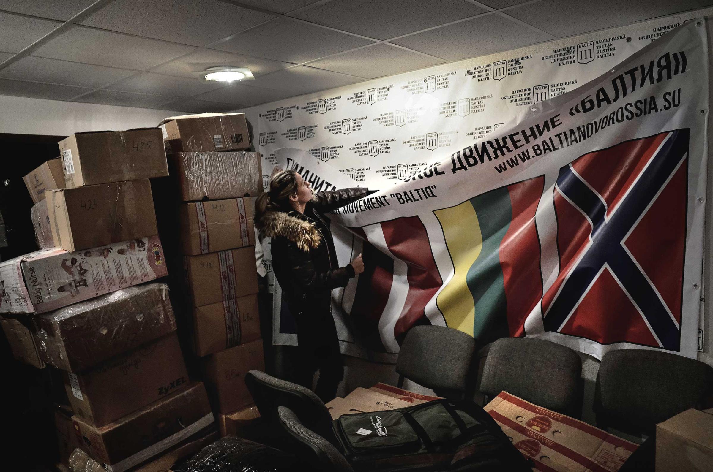 Inside the office of an organization in Riga, Latvia, that provides humanitarian aid to separatists in the East of Ukraine. A volunteer takes down a banner showing the flags of Estonia, Latvia, Lithuania and the self-proclaimed confederation of Novorossiya in the East of Ukraine.