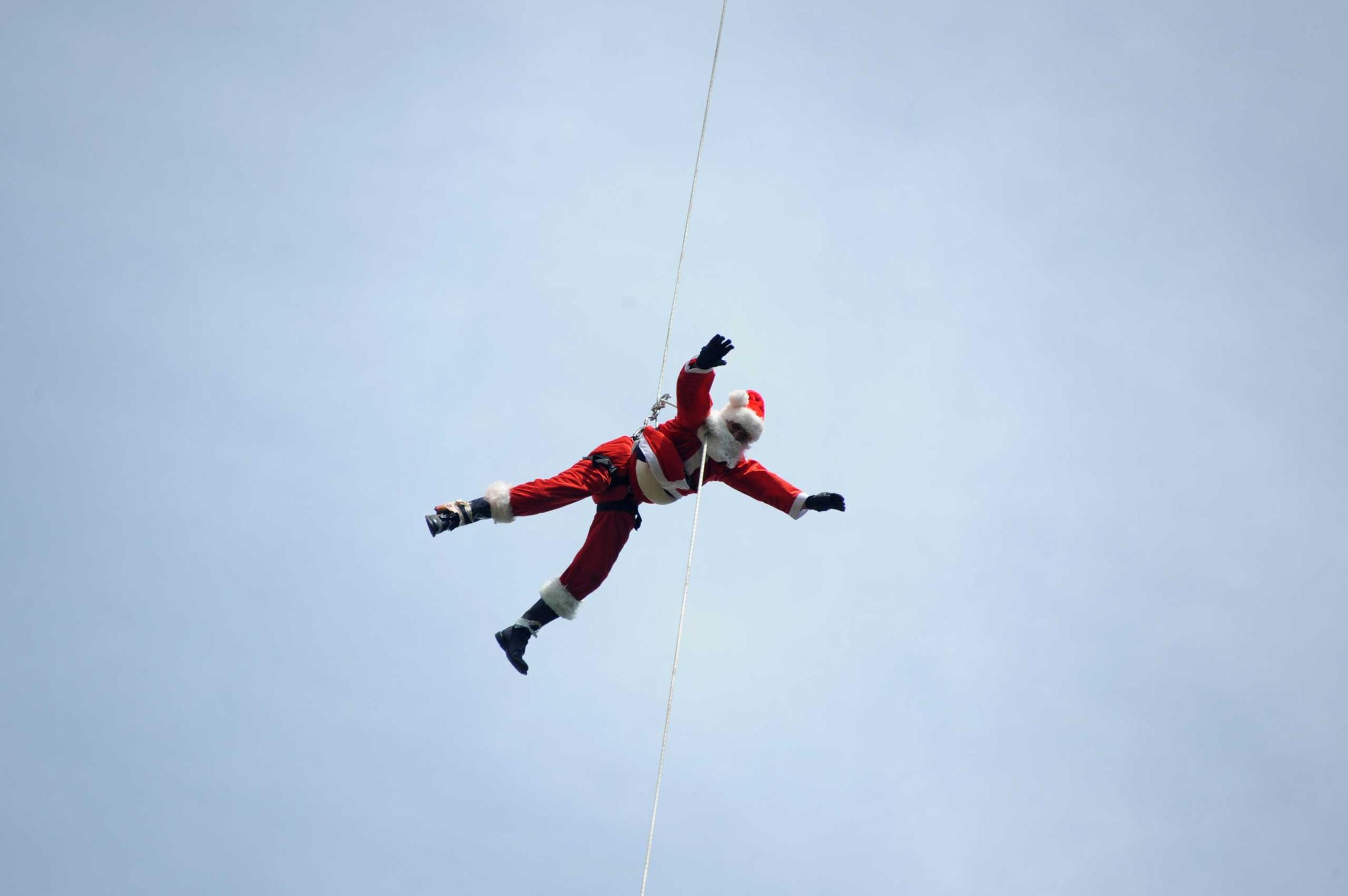 Guatemalan firefighter Hector Chacon dressed as Santa Claus goes down a cable from a bridge to deliver presents to children in Guatemala City on Dec. 21, 2014.