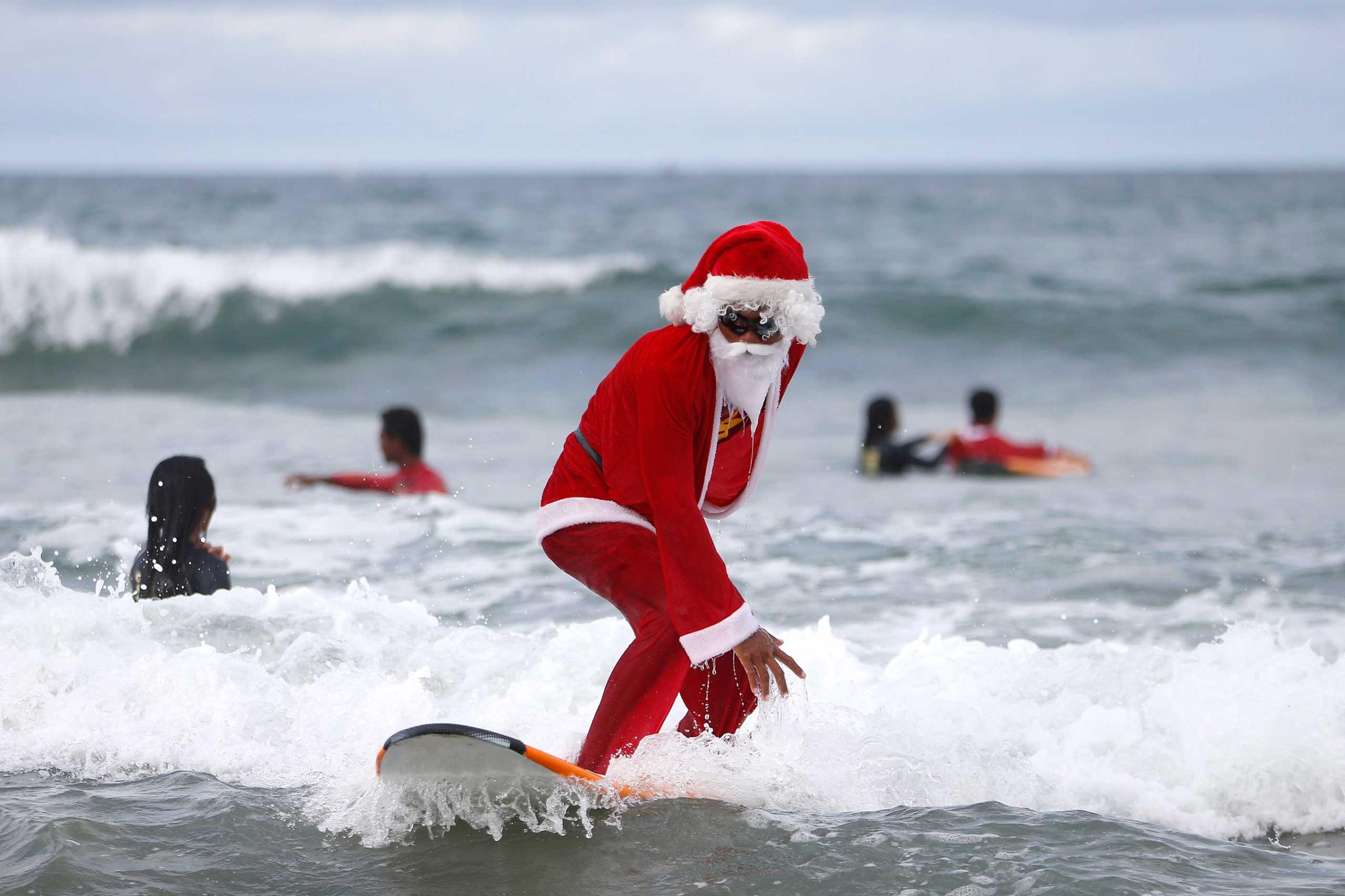 A Balinese man dressed as Santa Claus teaches orphan children how to surf at a beach in Bali, Indonesia on Dec. 7, 2014.