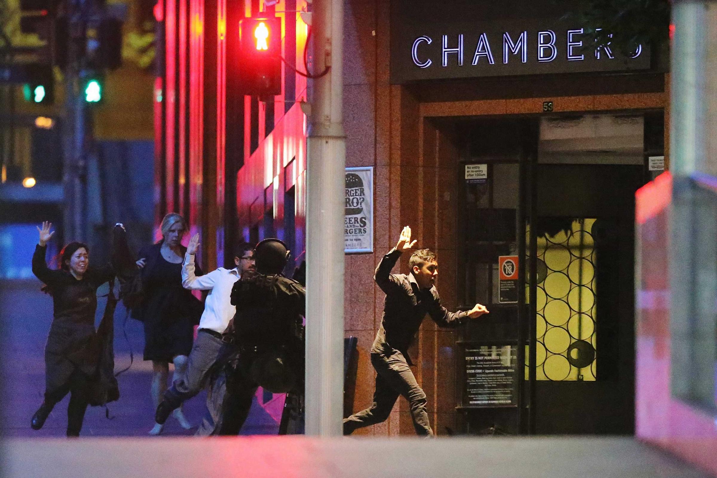 People run with there hands up from the Lindt Cafe, Martin Place during a hostage standoff on Dec. 15, 2014 in Sydney.