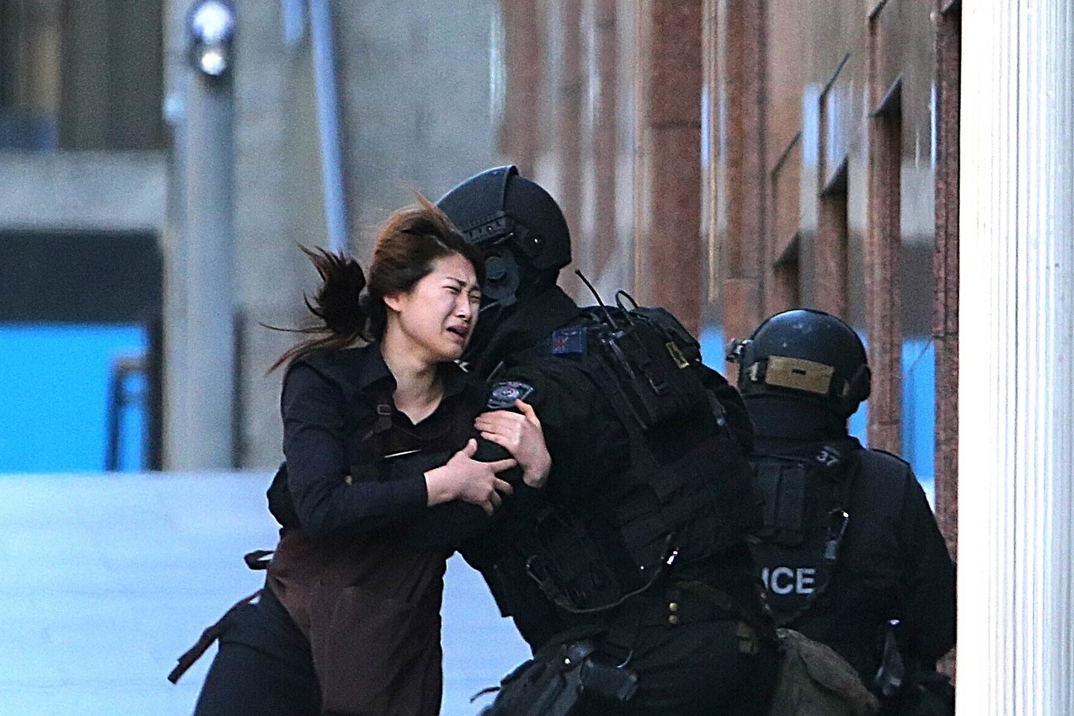 A hostage runs to tactical response police officers for safety after she escaped from a cafe under siege at Martin Place in Sydney, Australia, on Dec. 15, 2014. (Rob Griffith—AP)