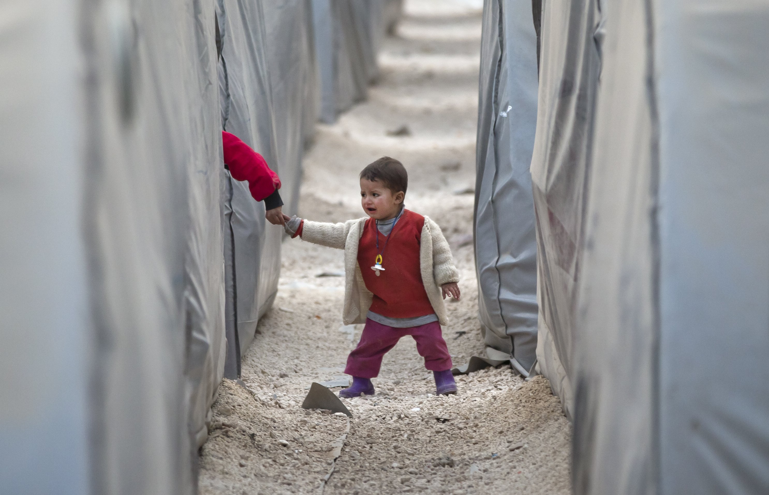 A Syrian Kurdish refugee child from the Kobani area holds another's hand as he walks between tents at a camp in Suruc, on the Turkey-Syria border on Nov. 14, 2014. (Vadim Ghirda—AP)