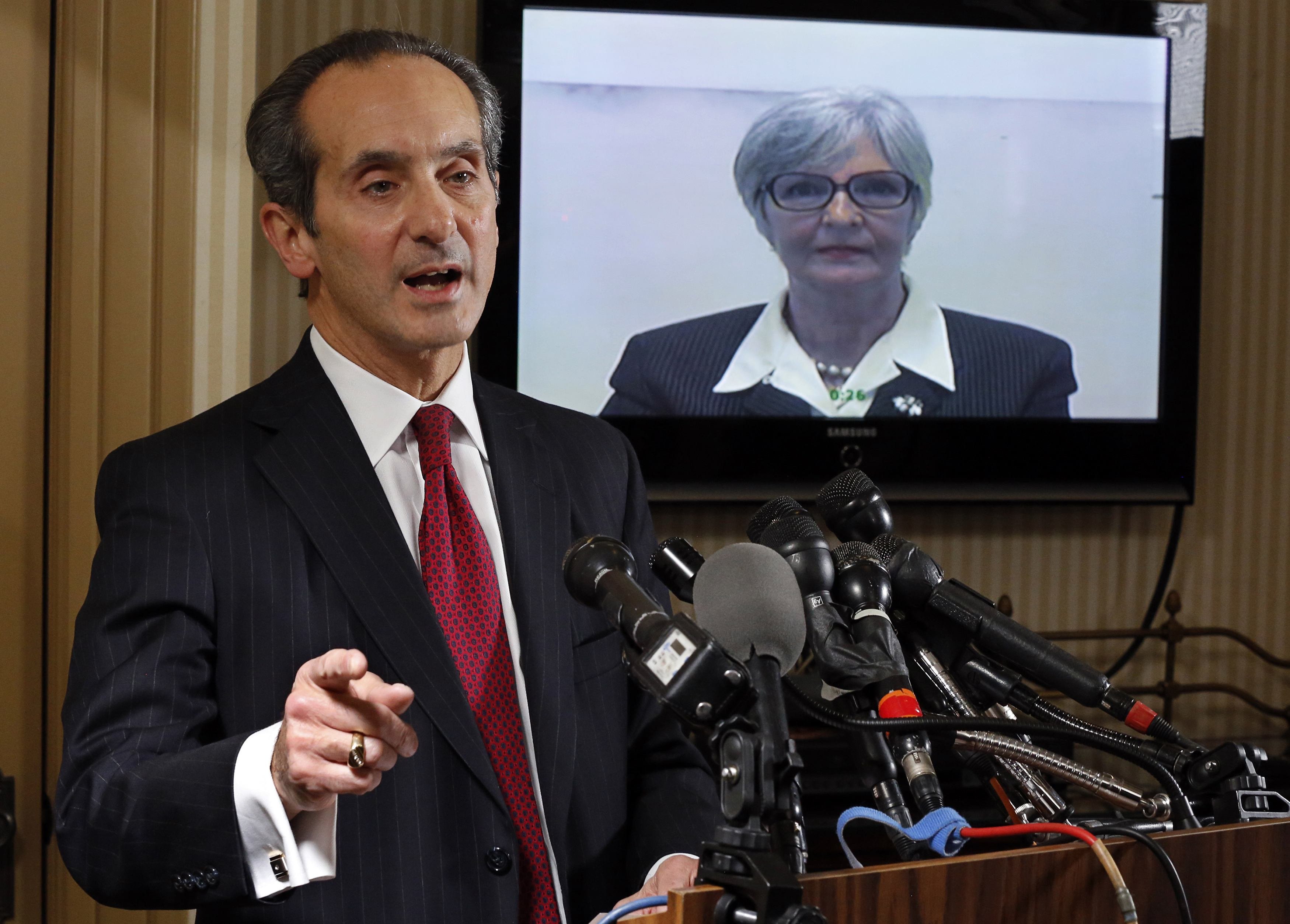 Tamara Green, the plaintiff in a defamation lawsuit claiming that she was "sexually assaulted by comedian Bill Cosby in the 1970s" watches by video link from California as her attorney Joseph Cammarata (L) speaks about the suit that they have filed to a news conference in Washington on Dec. 10, 2014.