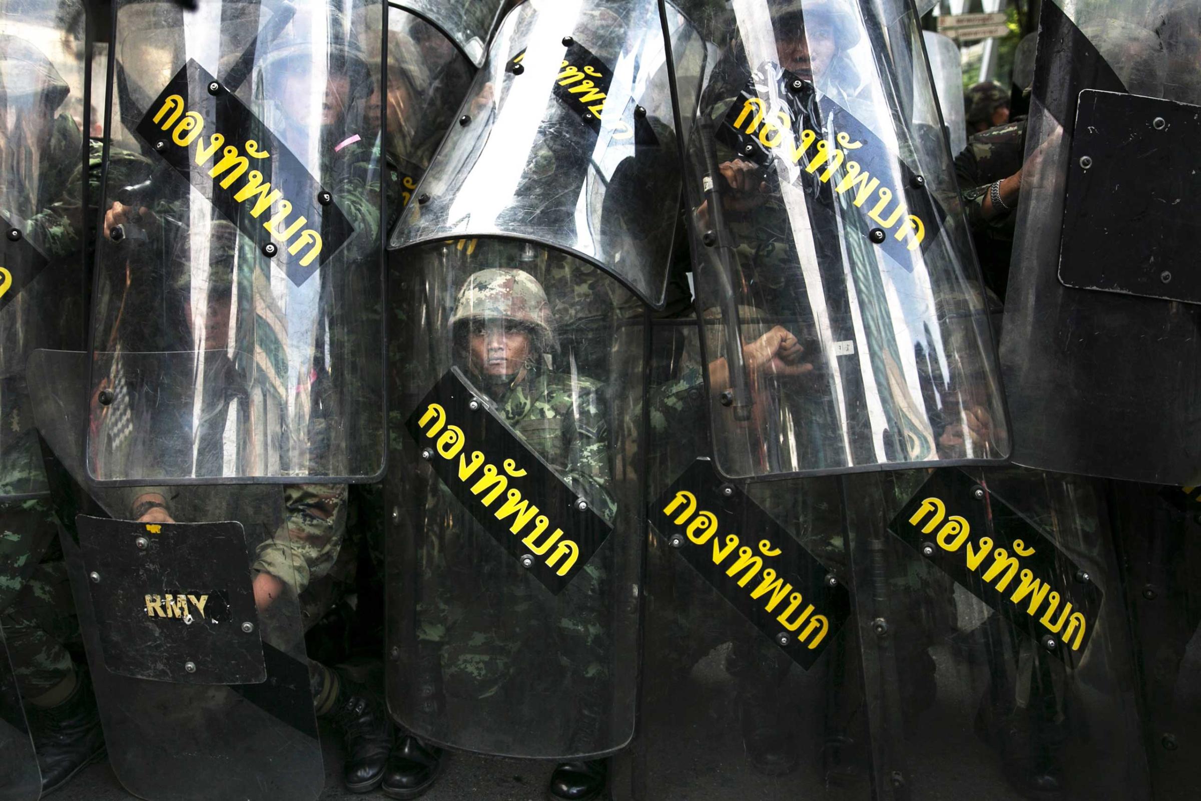 Thai military stand behind their riot shields as protesters threaten them during an anti-coup protest on the third day of the military coup May 25, 2014 in Bangkok, Thailand.