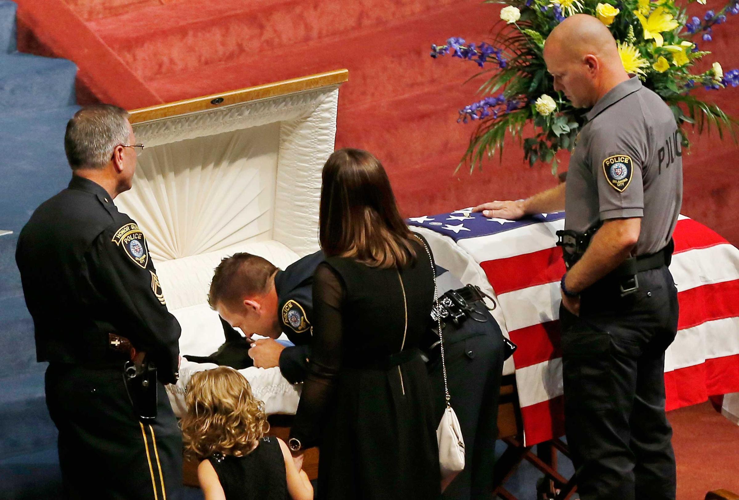 Oklahoma City police officer Sgt. Ryan Stark leans over the casket of his canine partner, K-9 Kye, following funeral services for the dog in Oklahoma City, Aug. 28, 2014.