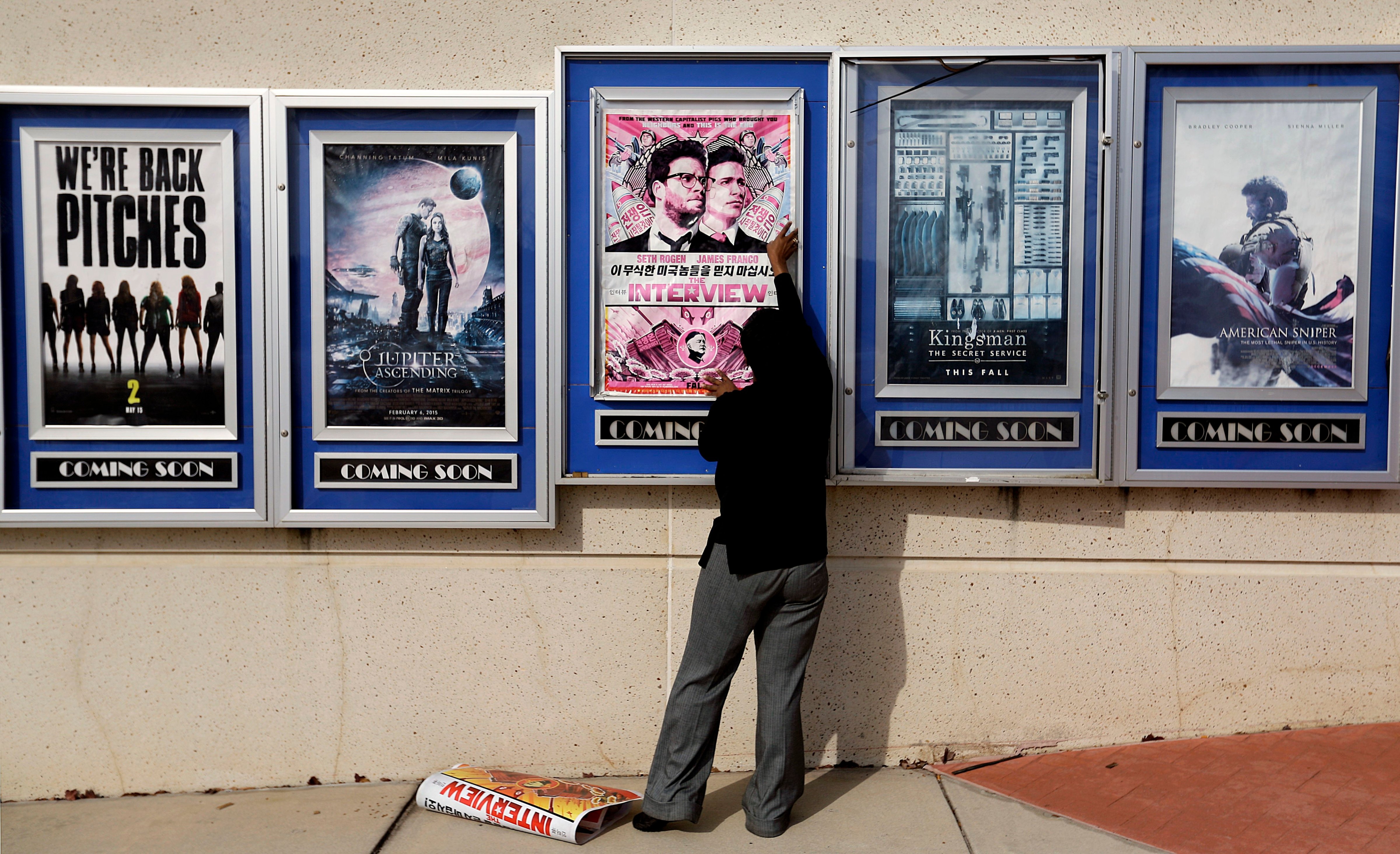 A poster for the movie "The Interview" is taken down by a worker after being pulled from a display case at a Carmike Cinemas movie theater, Wednesday, Dec. 17, 2014, in Atlanta.