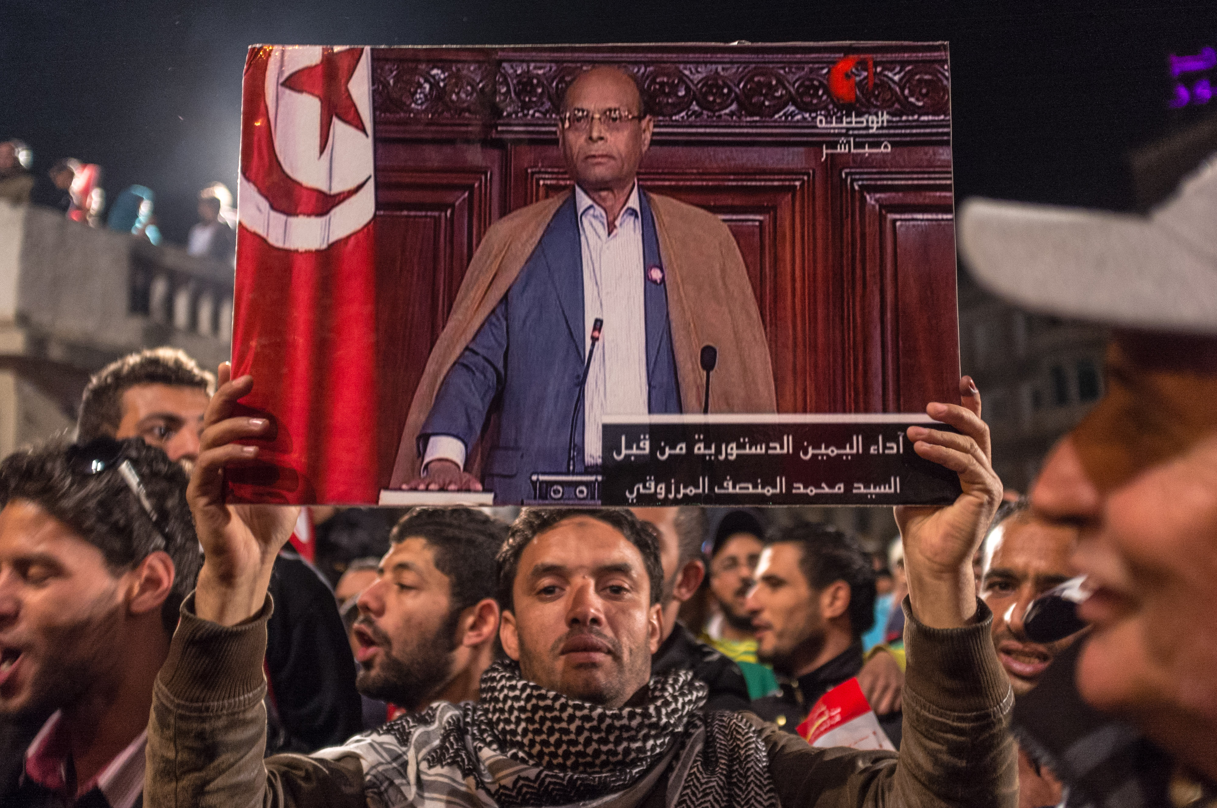 A man holds up a picture of Tunisian presidential candidate Moncef Marzouki, as supporters gather to hear his speech after the second round of the country's presidential election, in Tunis, Sunday, Dec. 21, 2014. (Ilyess Osmane—AP)