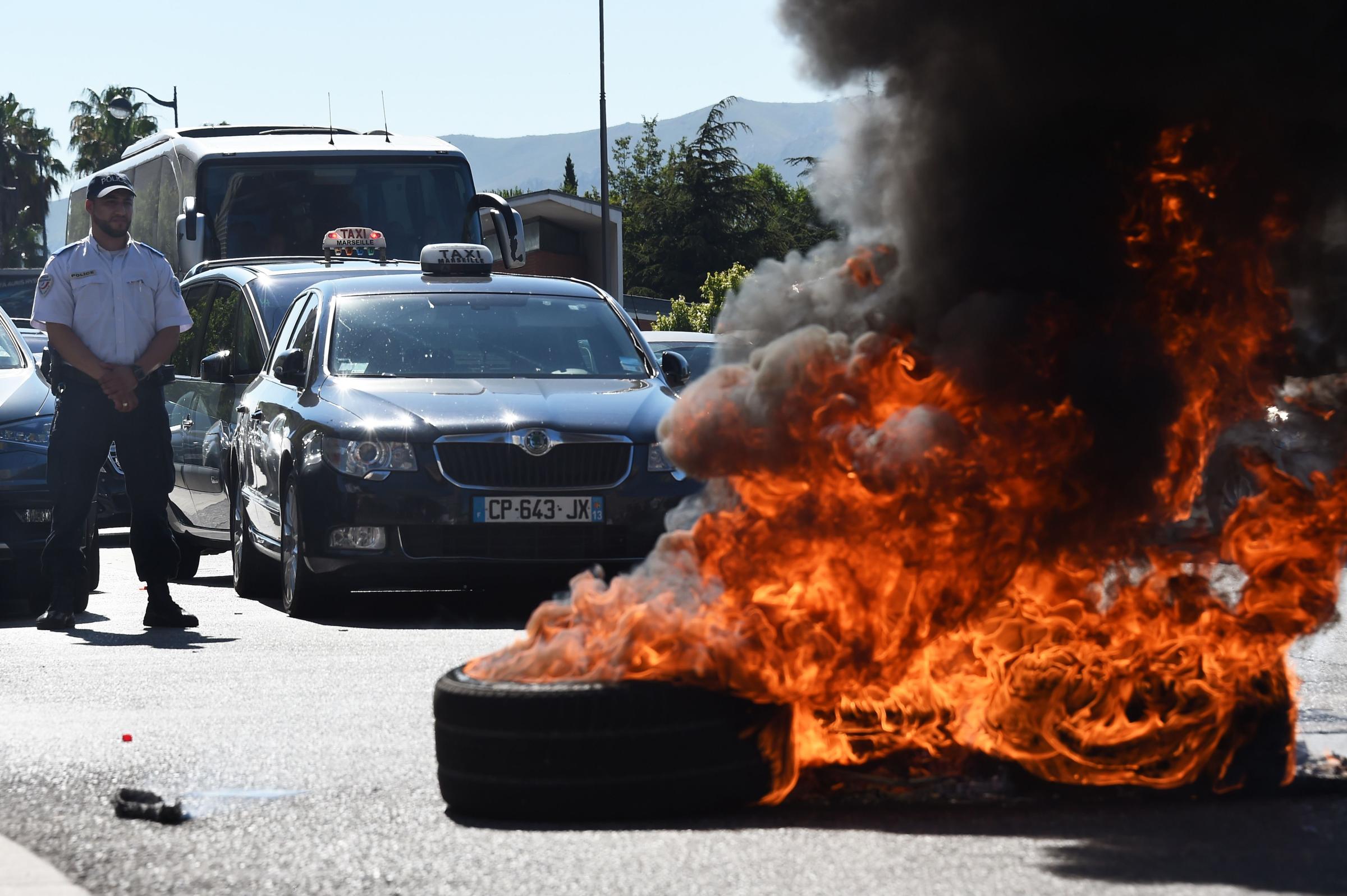 French Taxi drivers burn tires as they protest in the southern city of Marseille on June 25, 2015 as they demonstrate against UberPOP, a popular taxi app that is facing fierce opposition from traditional cabs.