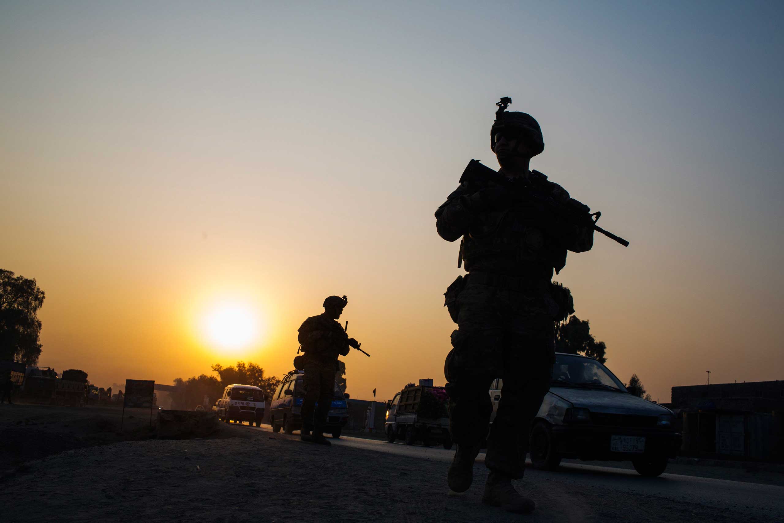 U.S. soldiers from Grim Company of the 3rd Cavalry Regiment walk down the street near an Afghan police checkpoint during a mission near Forward Operating Base Fenty in the Nangarhar province of Afghanistan on Dec. 19, 2014.
