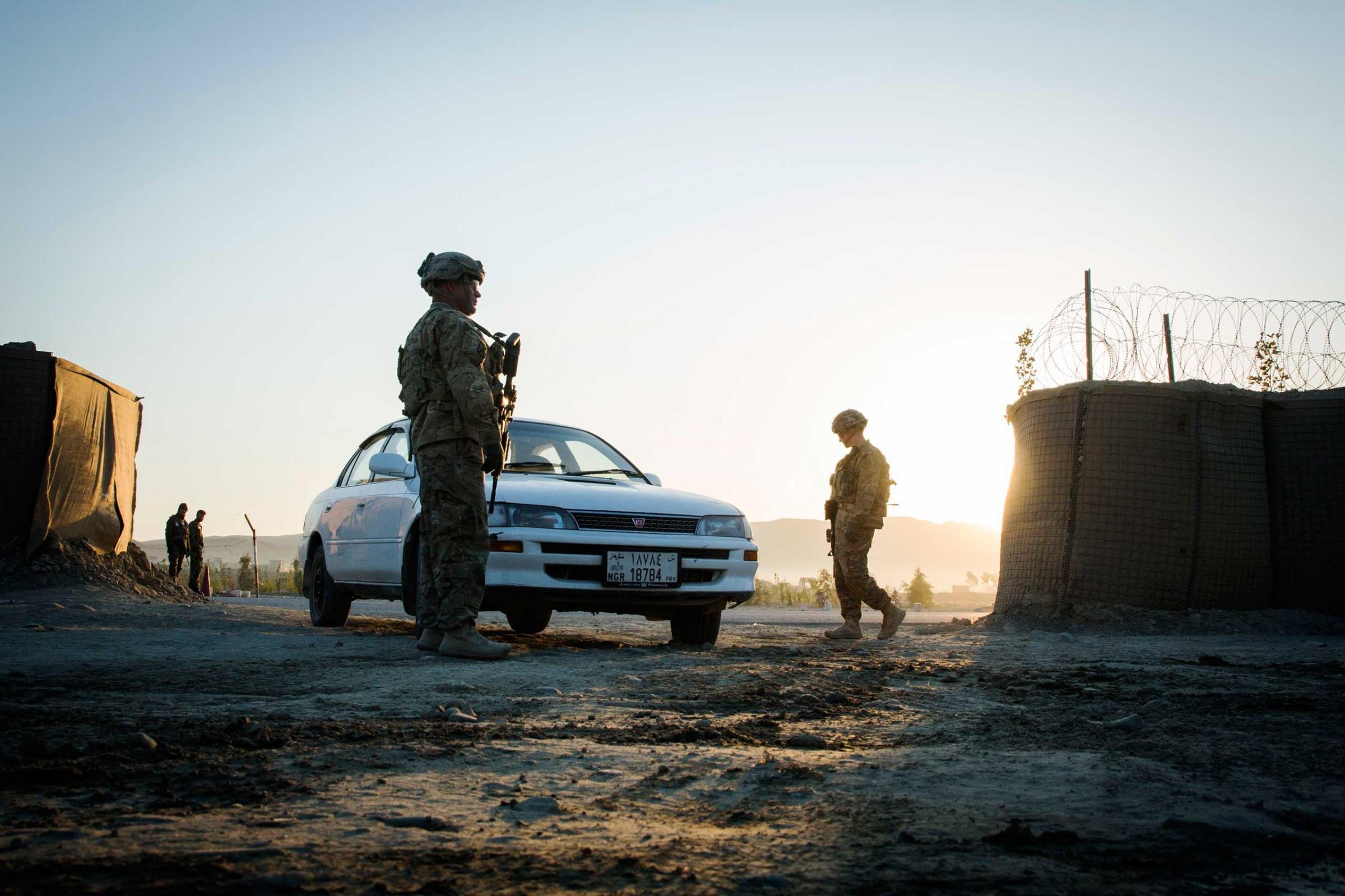 U.S. soldiers from 3rd Cavalry Regiment flag a car to stop to be screened for explosives near forward operating base Gamberi in the Laghman province of Afghanistan