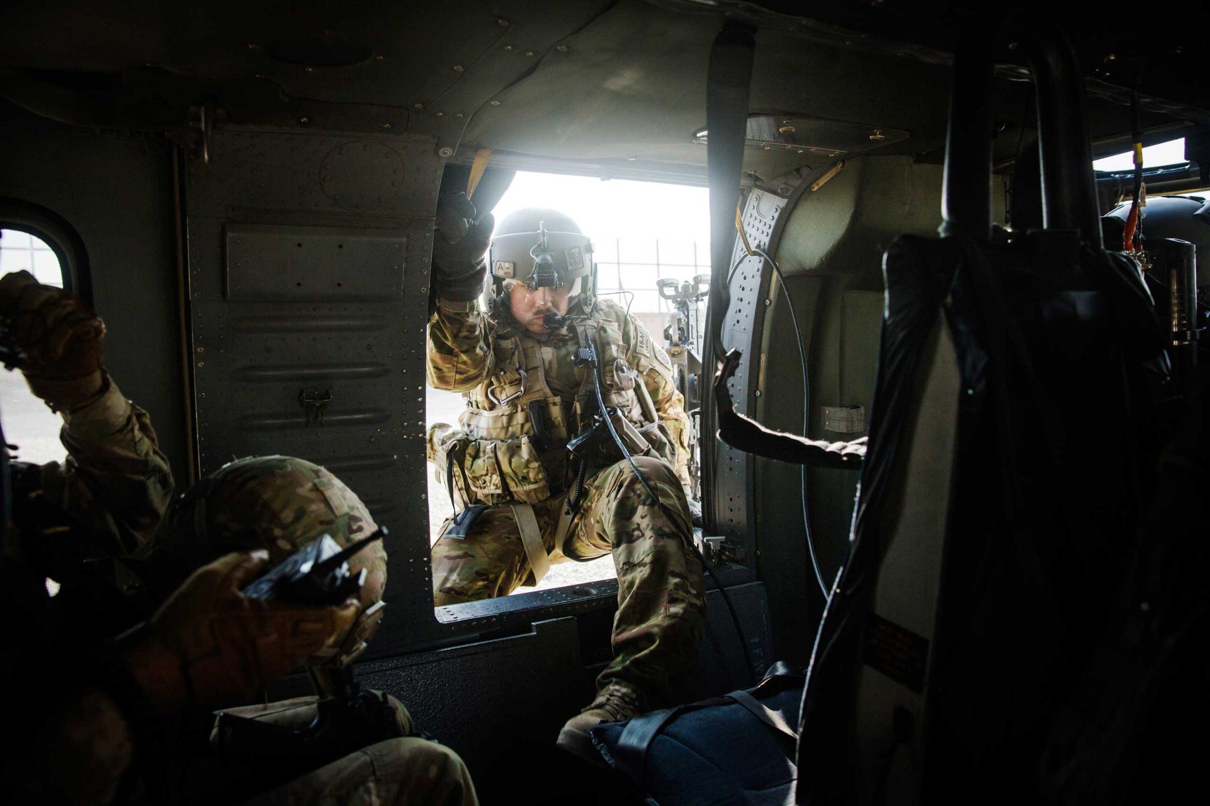 A crew member climbs into a U.S. Blackhawk helicopter before it takes off following a mission to take Brigadier General Christopher Bentley to inspect an Afghan National police installation in the Nangarhar province of Afghanistan