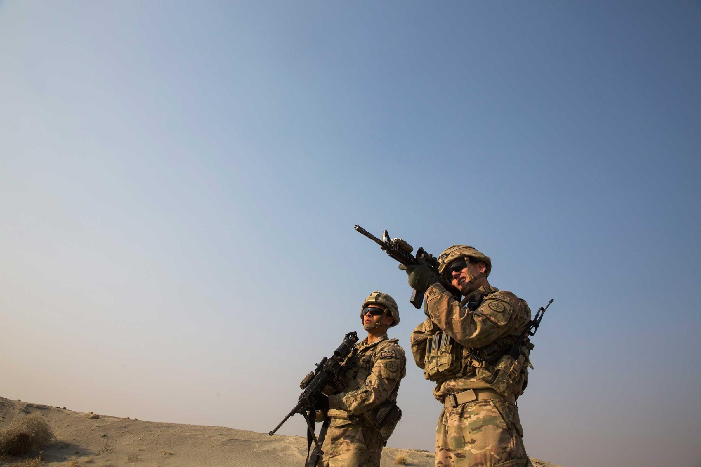 A U.S. soldier from the 3rd Cavalry Regiment uses the optic on his rifle to observe Afghans in the distance, near forward operating base Gamberi, in the Laghman province of Afghanistan