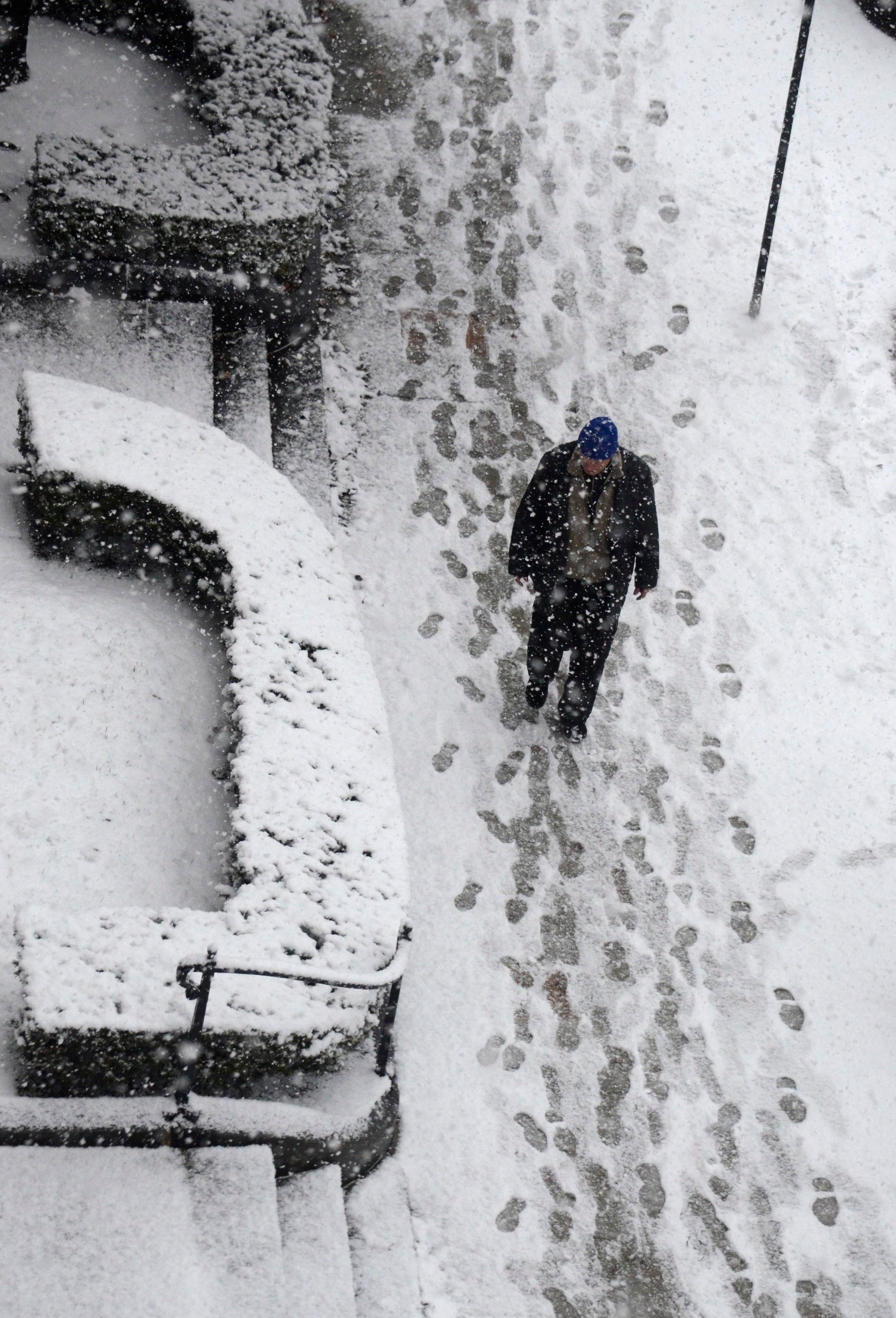 A man walks in snow in Pittsfield, Mass., as snow accumulates on the sidewalk on Dec. 10, 2014.