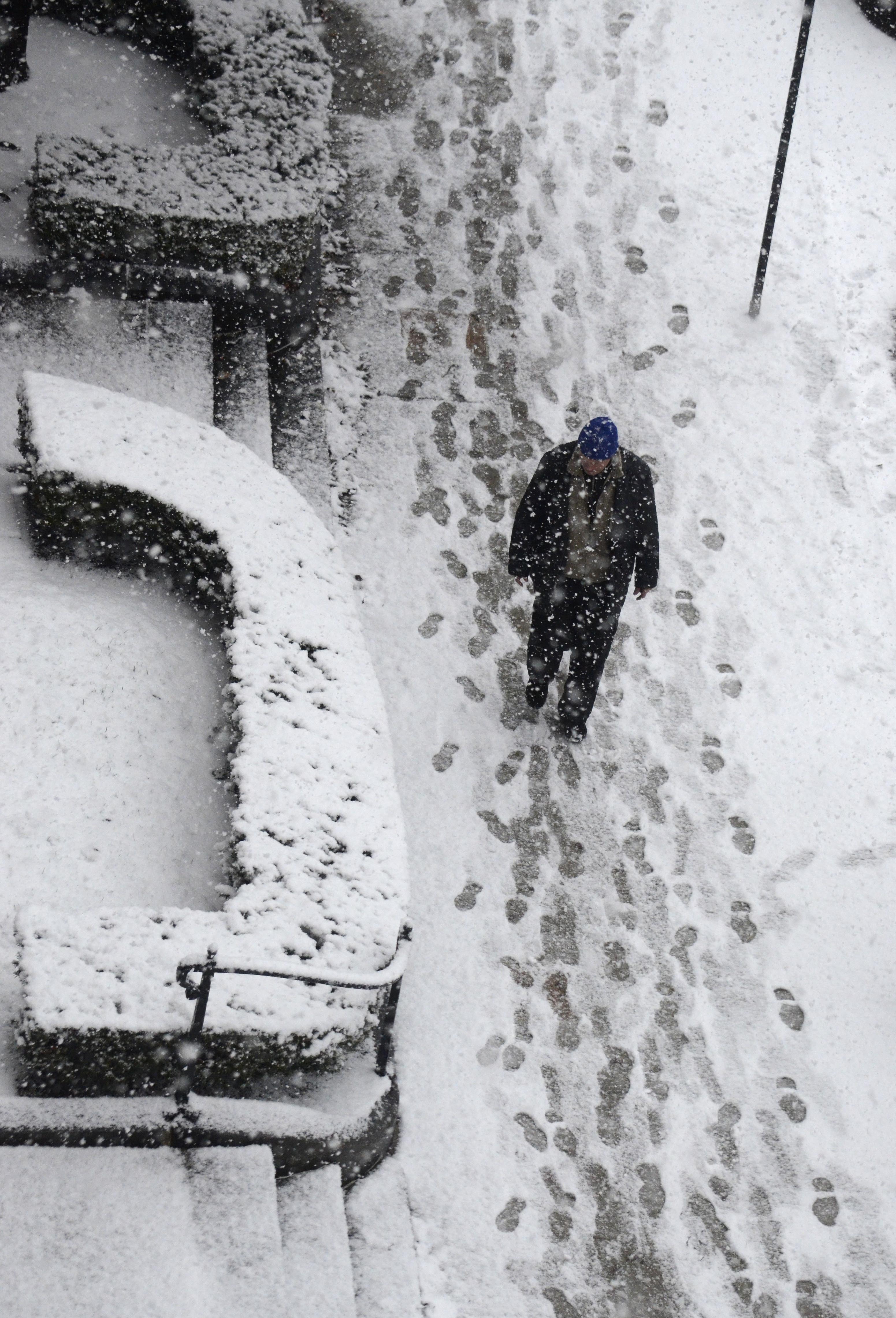 A man walks in snow in Pittsfield, Mass., as snow accumulates on the sidewalk on Dec. 10, 2014. (Ben Garver—AP)