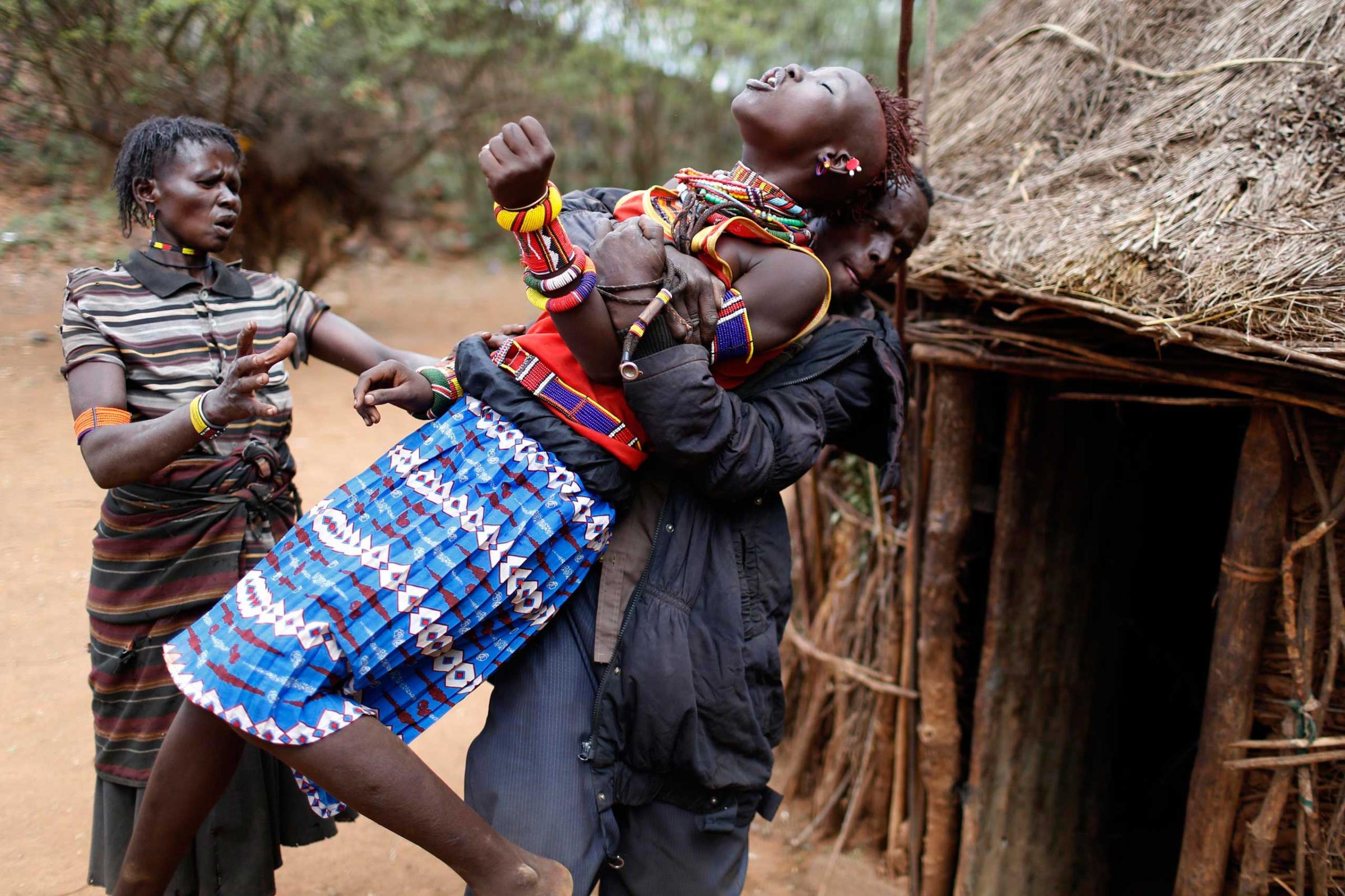A man holds a girl as she tries to escape when she realised she is to to be married, about 80 km (50 miles) from the town of Marigat in Baringo County