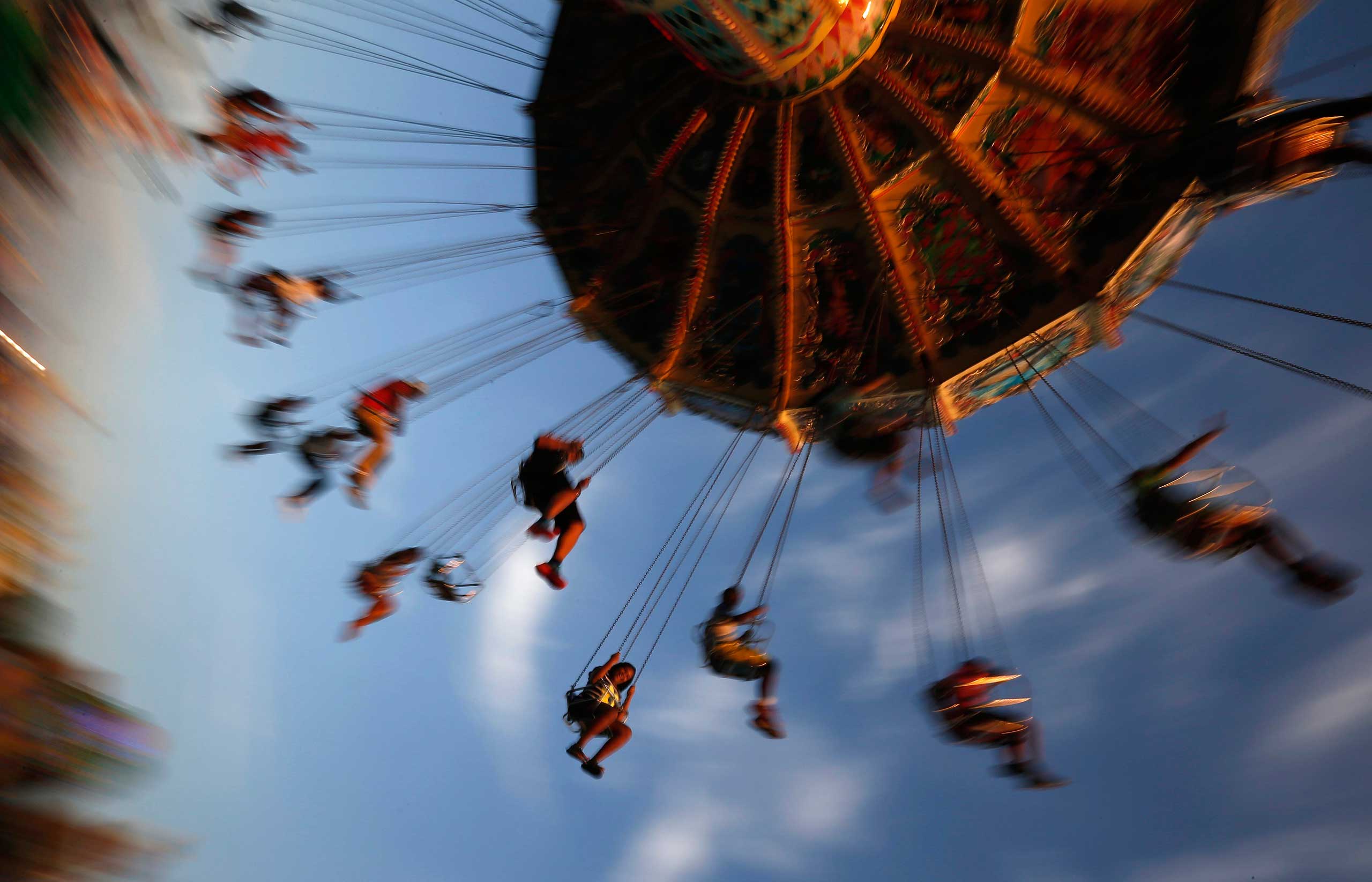 People ride on a swing at the Wisconsin State Fair in West Allis, Wisconsin, August 9, 2014. The fair started over 150 years ago and mixes agricultural exhibits with amusements rides.
