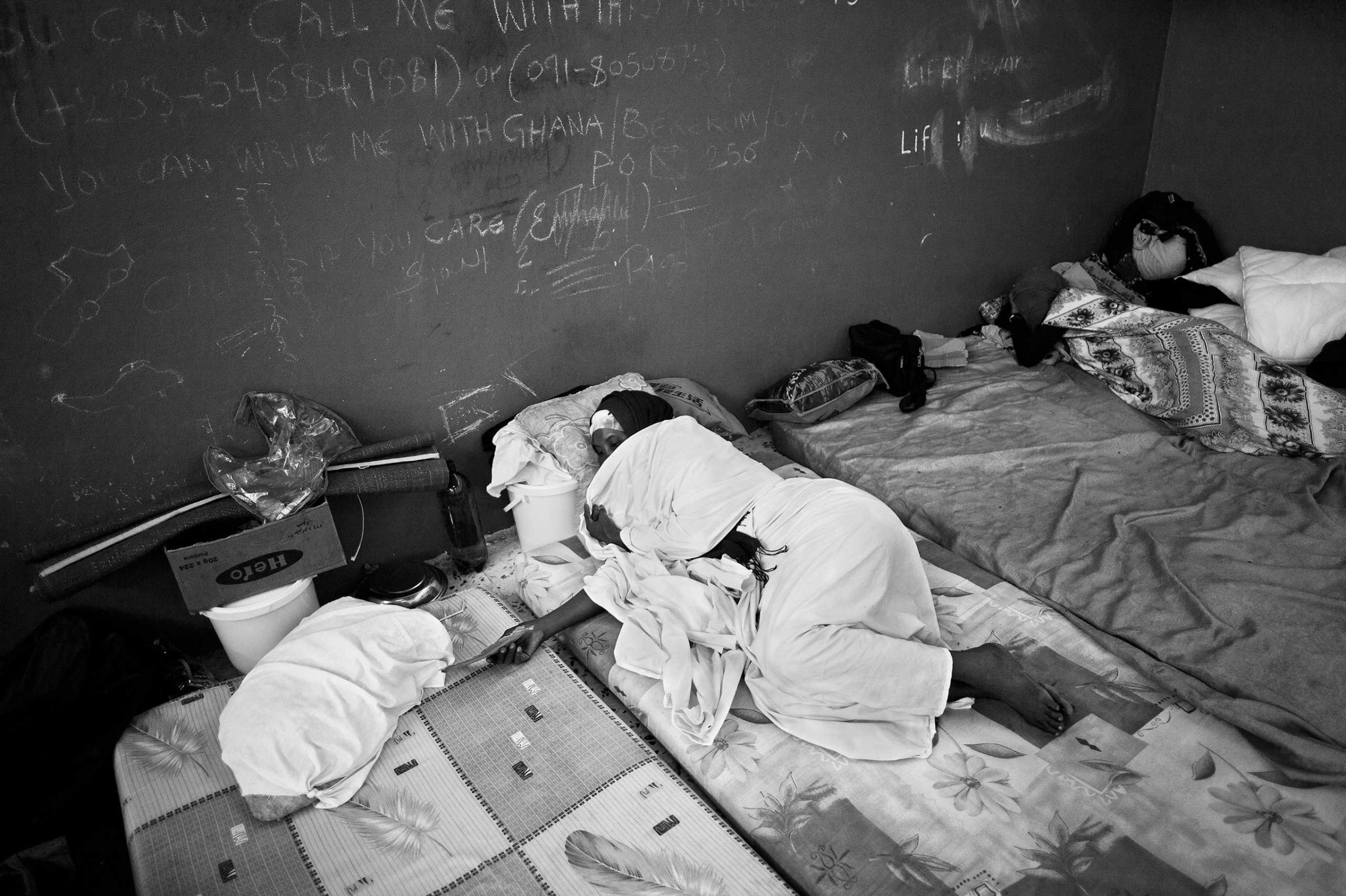 Migrants from Somalia is seen sleeping on a mattress on the floor barrack at a detention center for migrants near Maytigha Airport in Tripoli, Libya, Nov. 2013