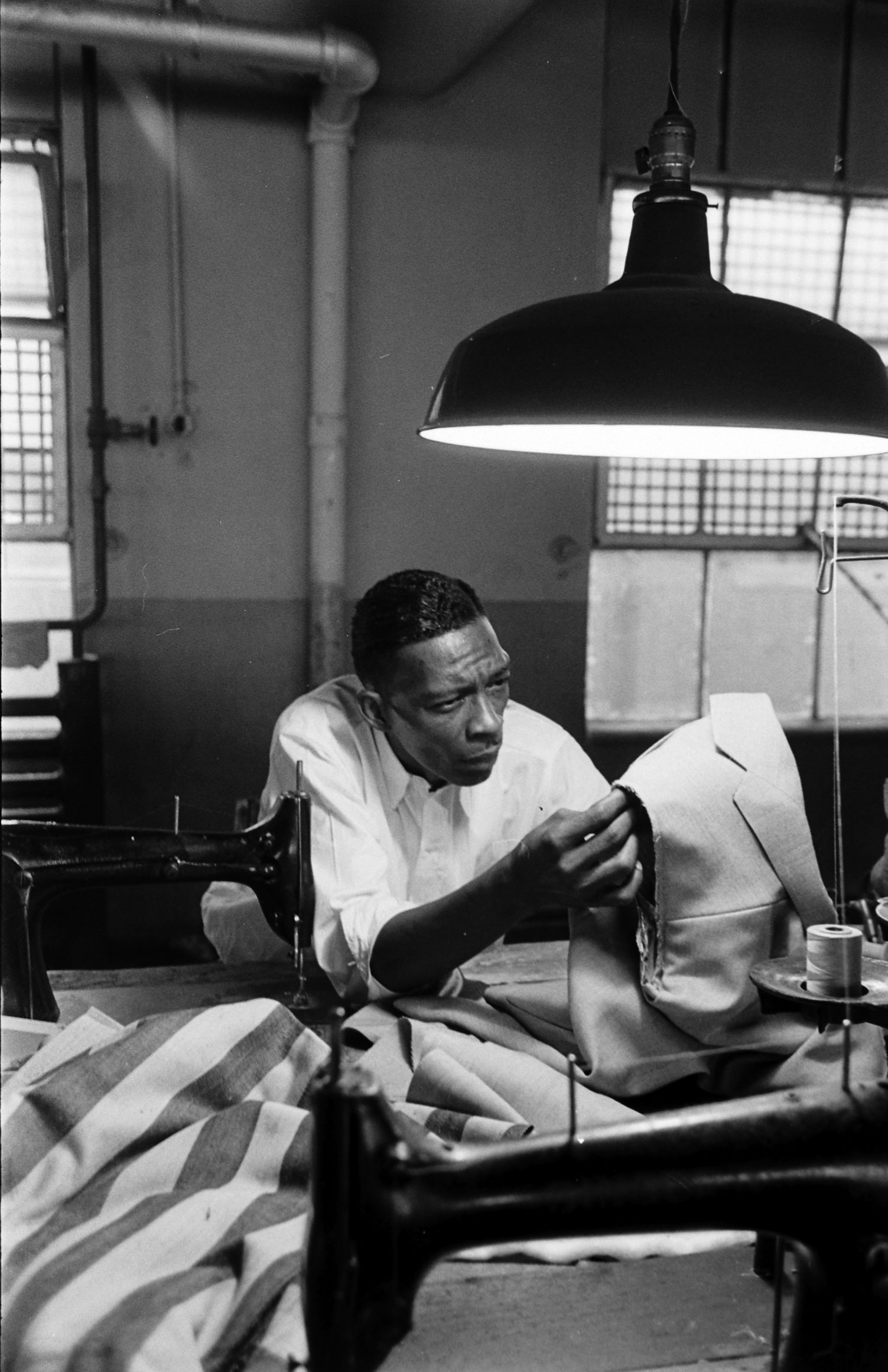 Prisonaire and convicted murderer Ed Thurman inspects cloth in prison textile school, Tennessee State Penitentiary, 1953.