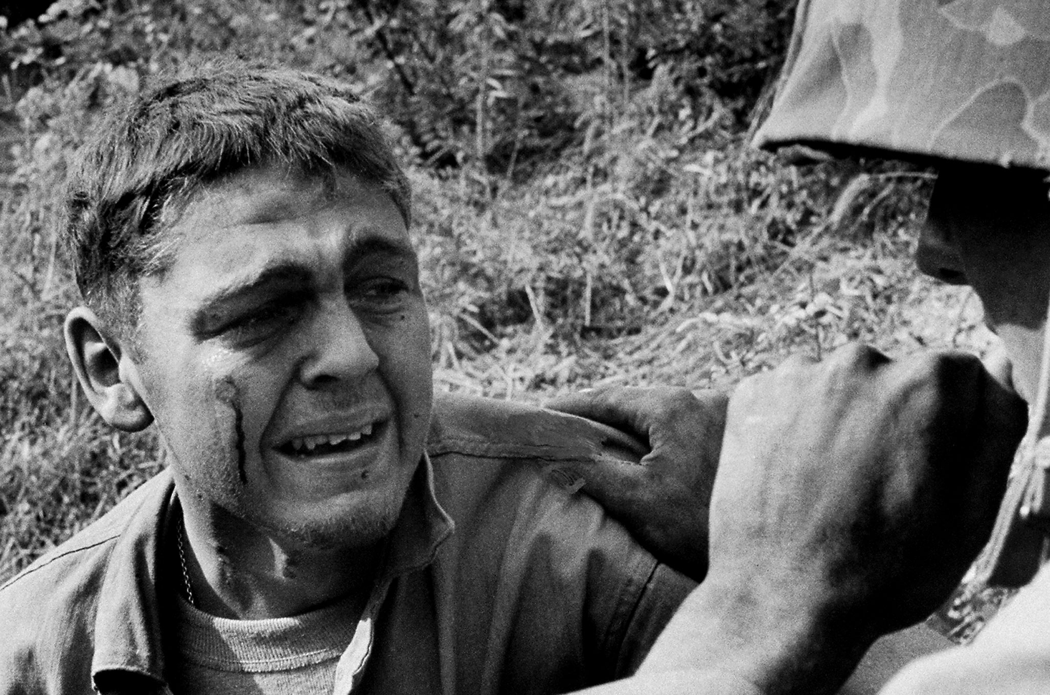 Wounded when a mine blew up his Jeep, an ambulance driver sobs by the side of the road after learning that a friend was killed in the blast, Korea 1950.