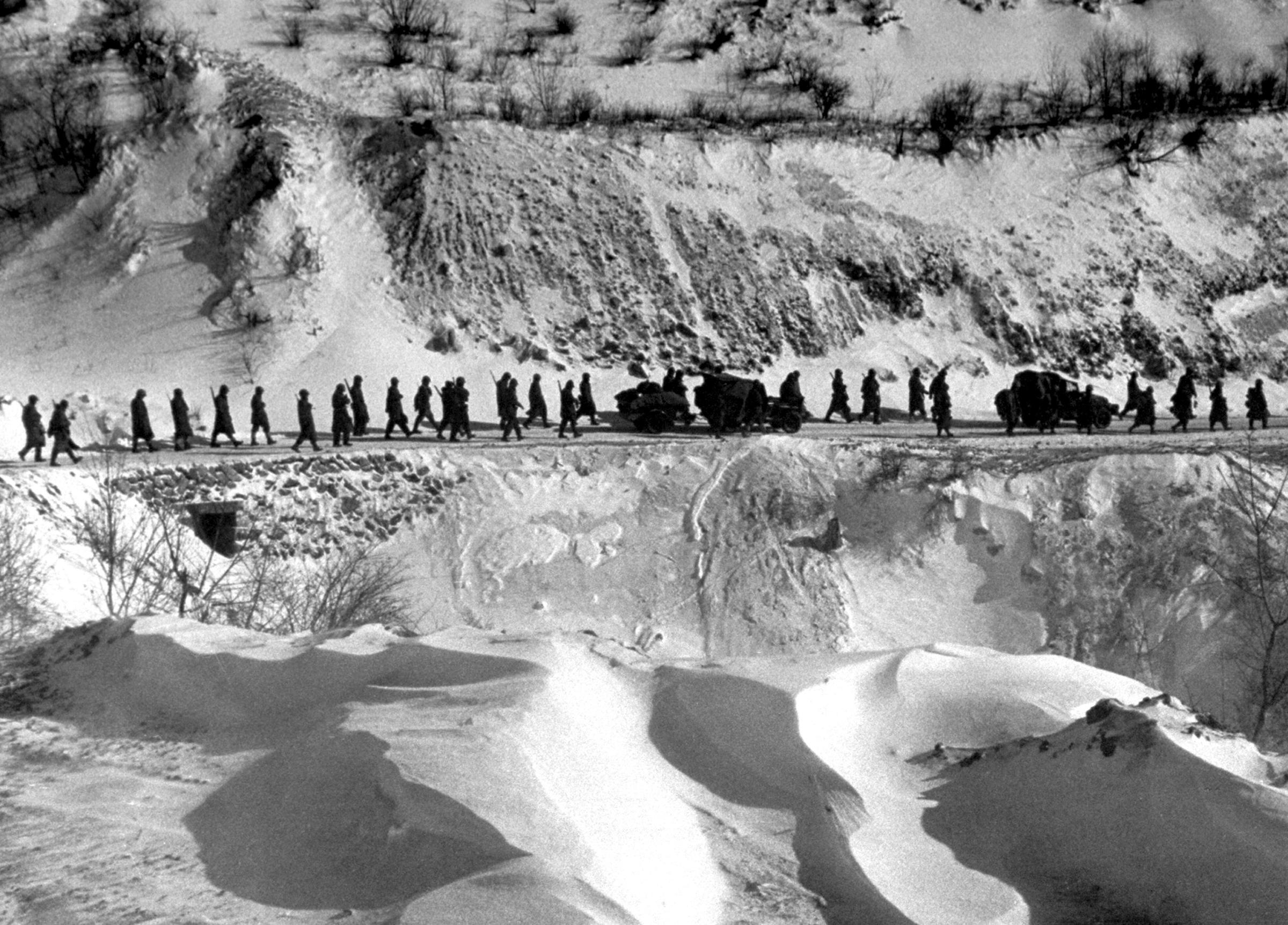 A column of American Marines marches down a canyon road dubbed "Nightmare Alley" during their retreat from Chosin Reservoir, Korea, 1950.
