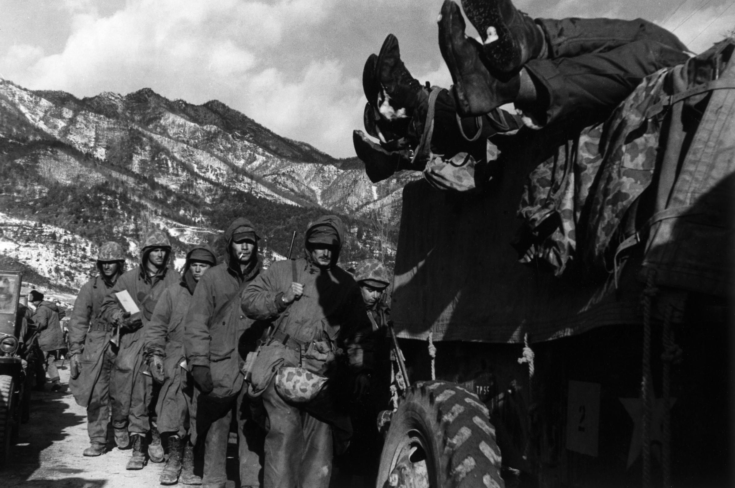 Marines file past a truck loaded with dead troops during the retreat from the Chosin Reservoir, December 1950.