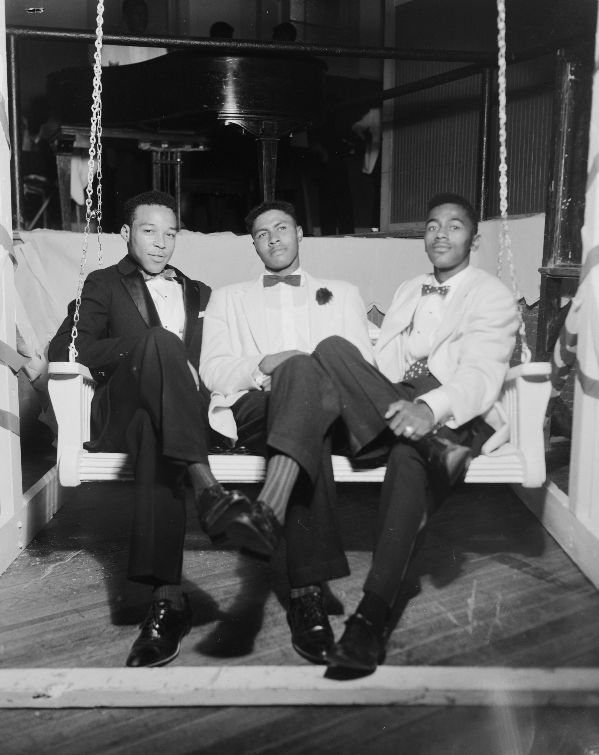 Douglas Burns, Charles Henry Sayles, and Alfred A. Neal sitting on a porch swing, 1958.
