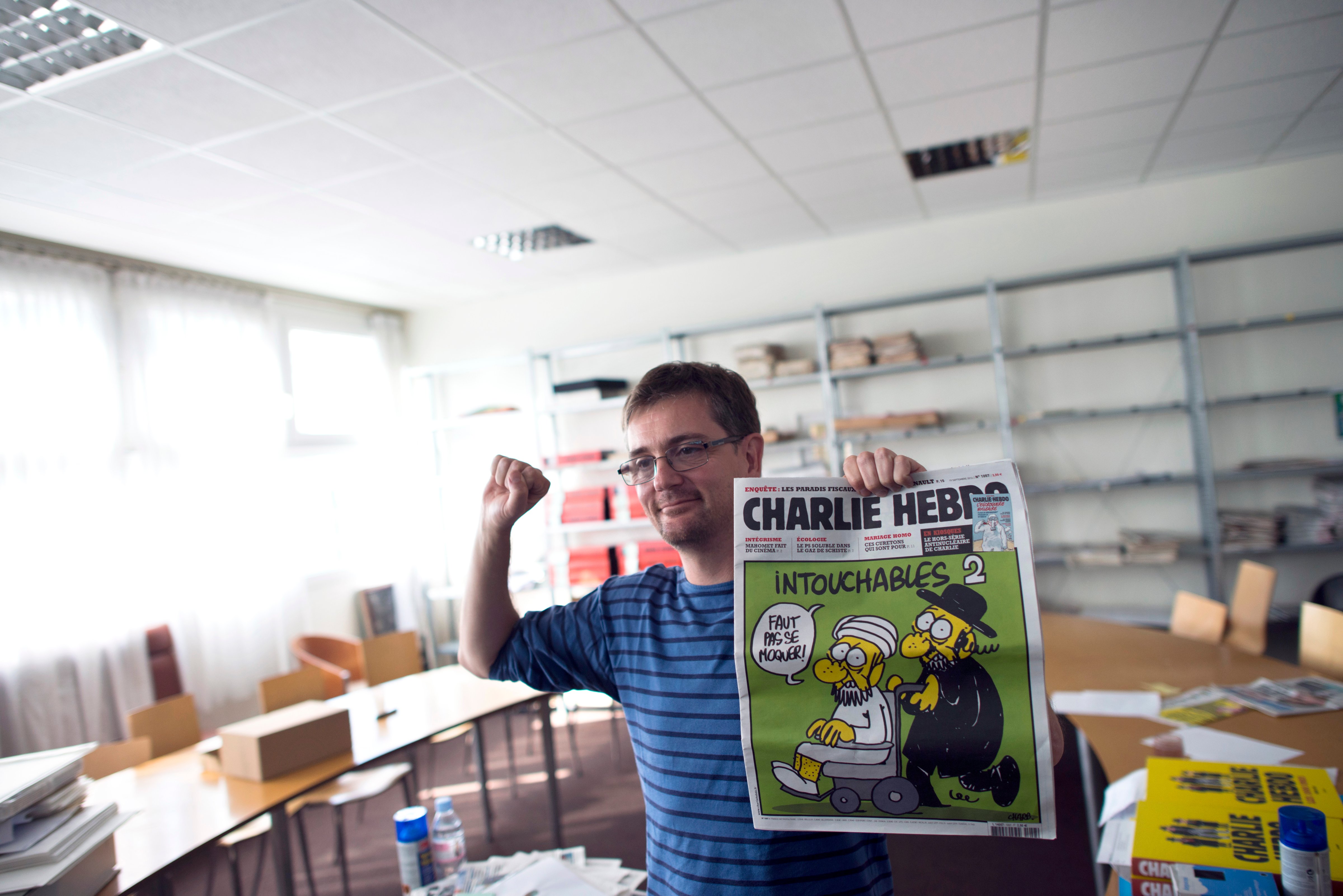 French satirical weekly <i>Charlie Hebdo</i>'s editor and cartoonist St&eacute;phane Charbonnier clenches his fist as he presents to journalists, on Sept. 19, 2012, at the weekly's headquarters in Paris, the latest issue that features on the front cover a satirical drawing entitled "Intouchables 2." Inside pages contain several cartoons of the Prophet Muhammad (Fred Dufour&mdash;AFP/Getty Images)