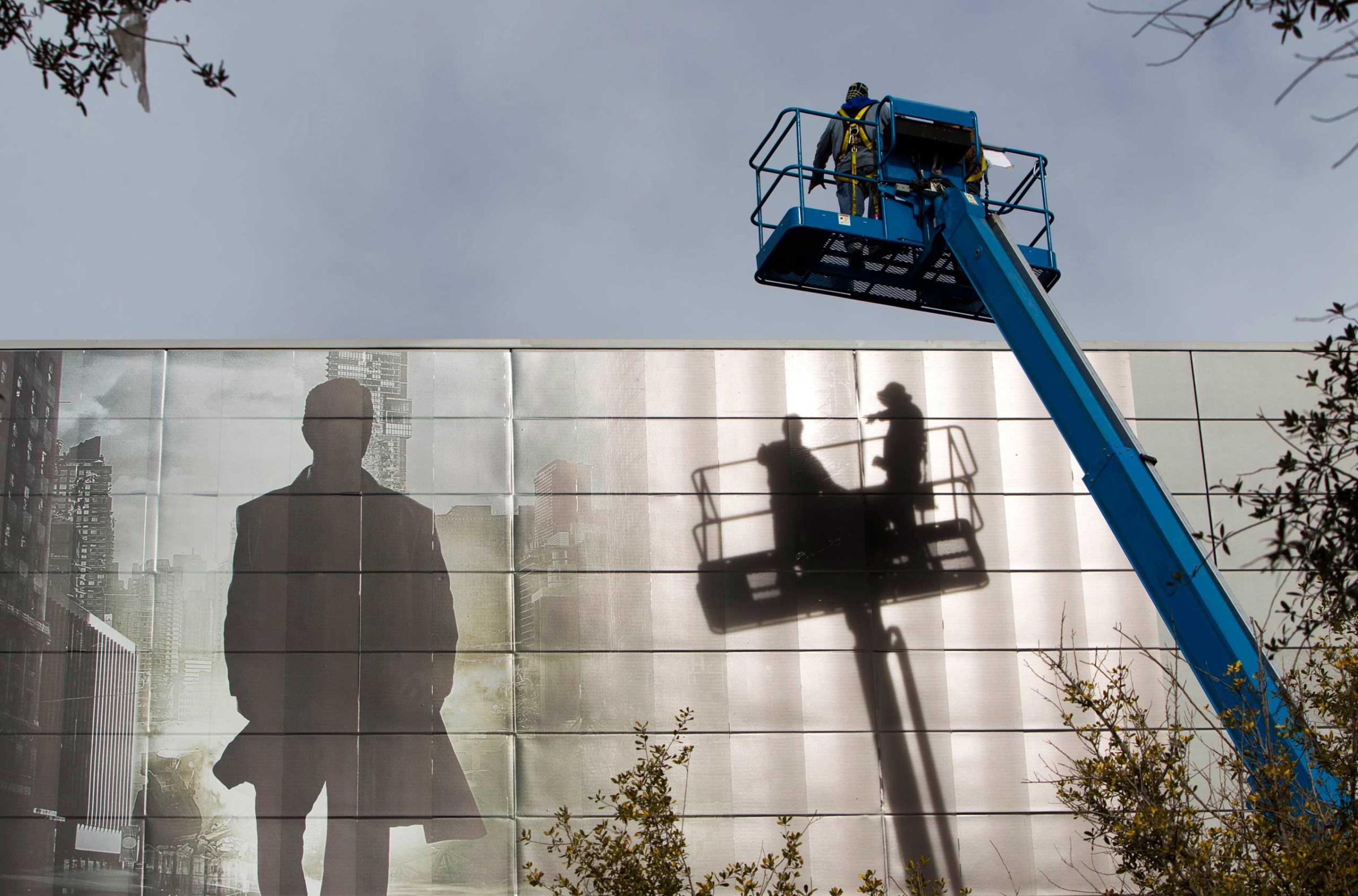 Workers install an advertisement for a new S'UHD TV from Samsung Electronics on the side of the Las Vegas Convention Center on Jan. 4, 2015.