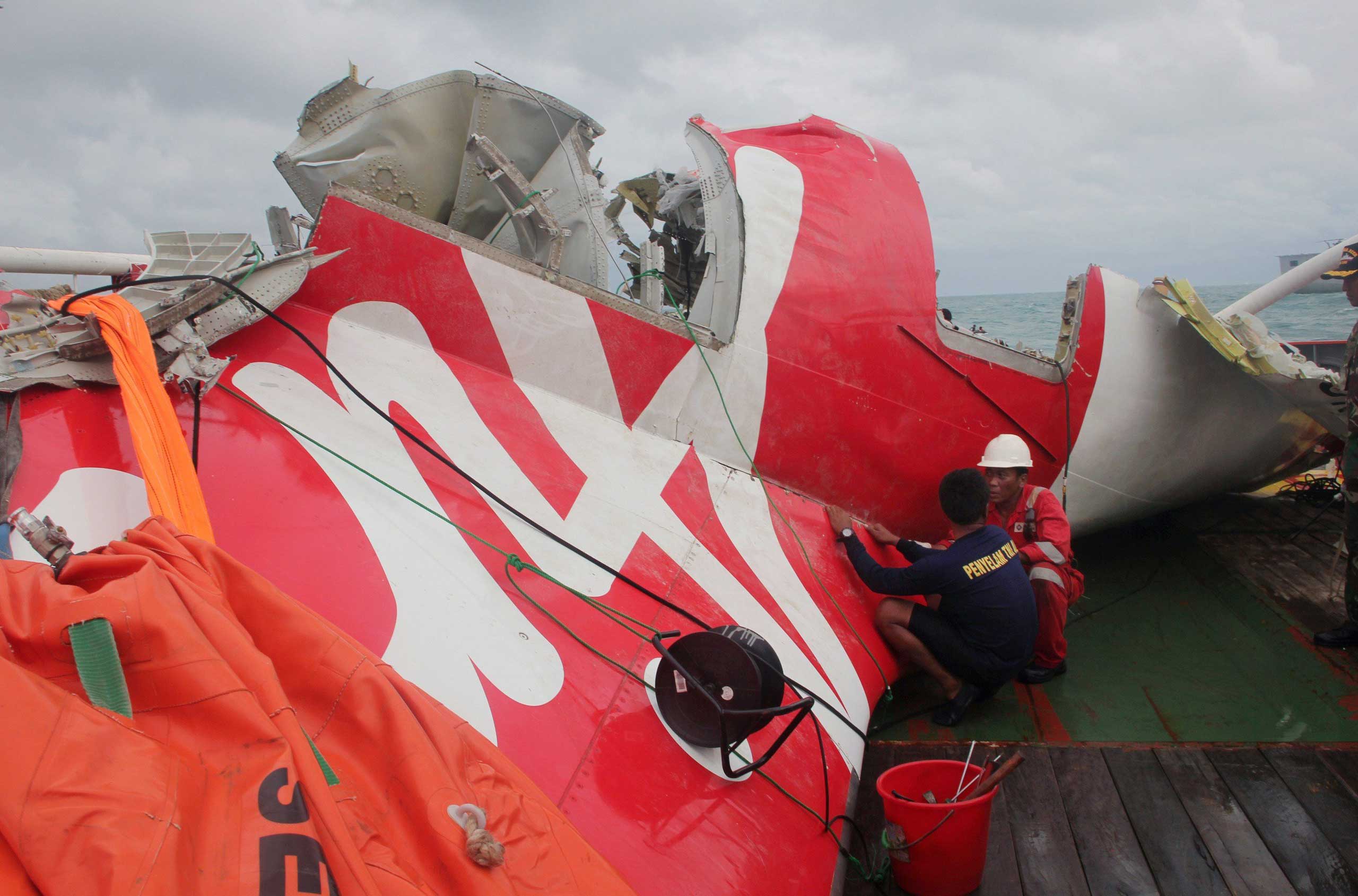 An Indonesian diver and an official examine the wreckage from AirAsia flight QZ8501 after it was lifted into the Crest Onyx ship at sea, near Indonesia on Jan. 10, 2015. (AFP/Getty Images)