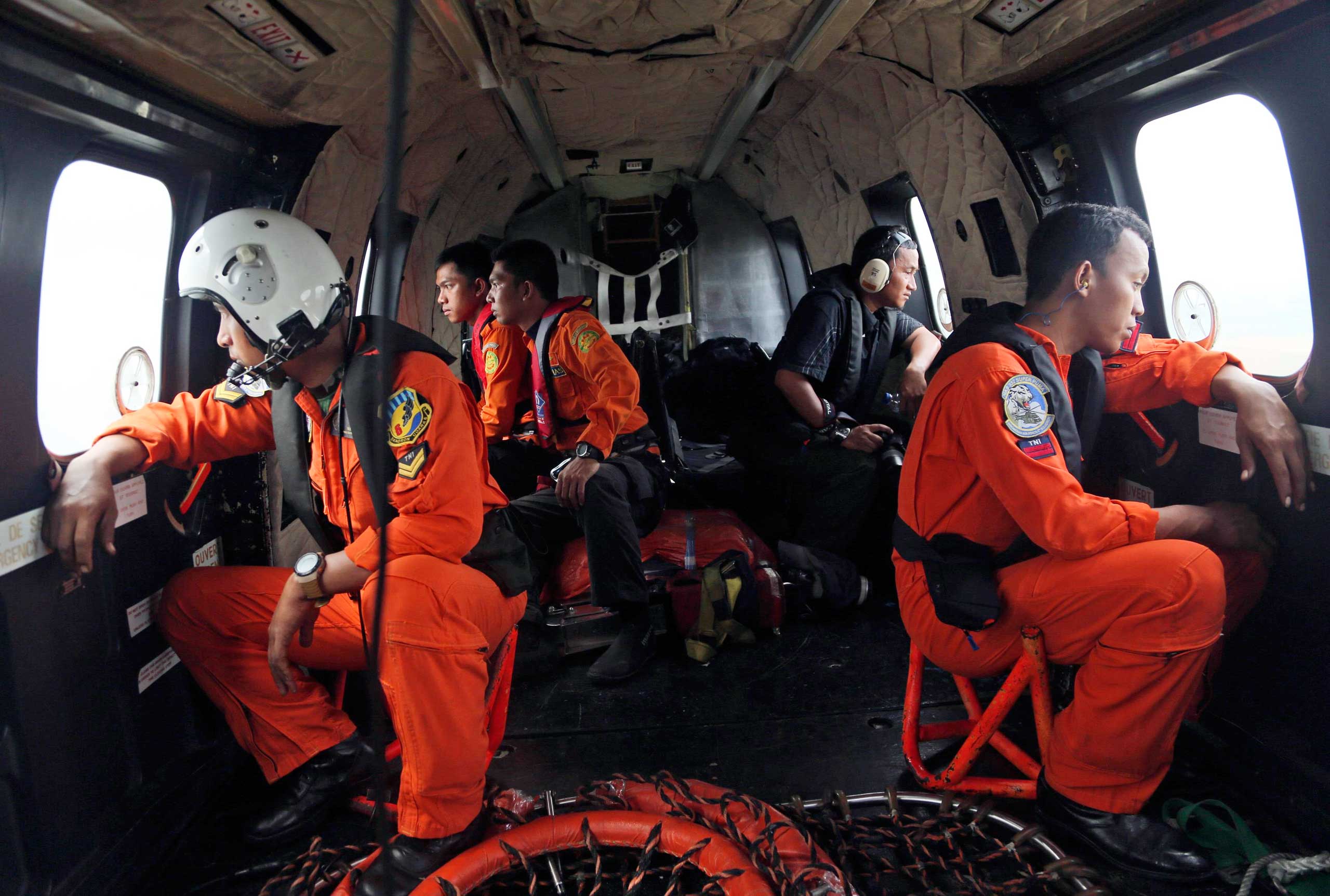 Crewmembers of an Indonesian Air Force NAS 332 Super Puma helicopter look out of the windows during a search operation for the victims and wreckage of AirAsia flight QZ 8501 over the Java Sea