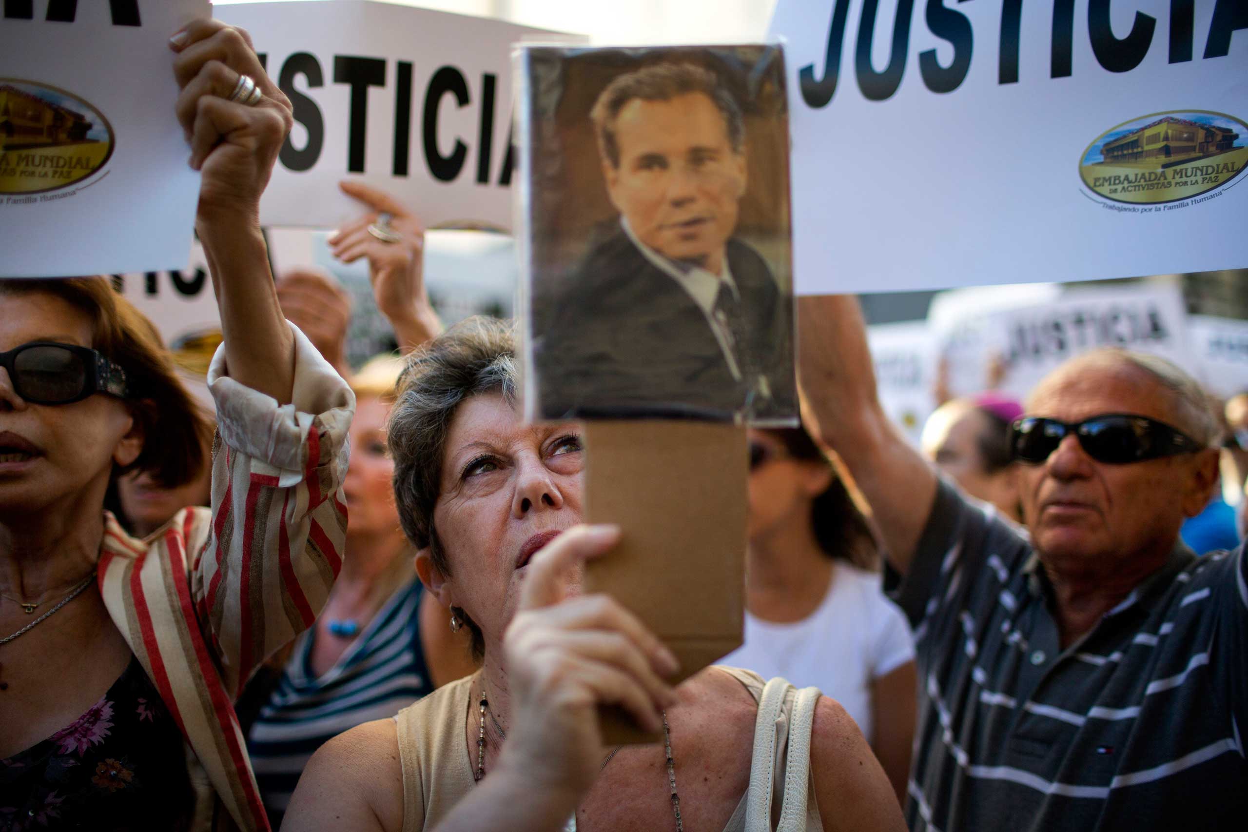 A woman chants the Argentine national anthem holding a portrait of the late prosecutor Alberto Nisman outside the AMIA Jewish community center in Buenos Aires, Jan. 21, 2015. (Rodrigo Abd—AP)