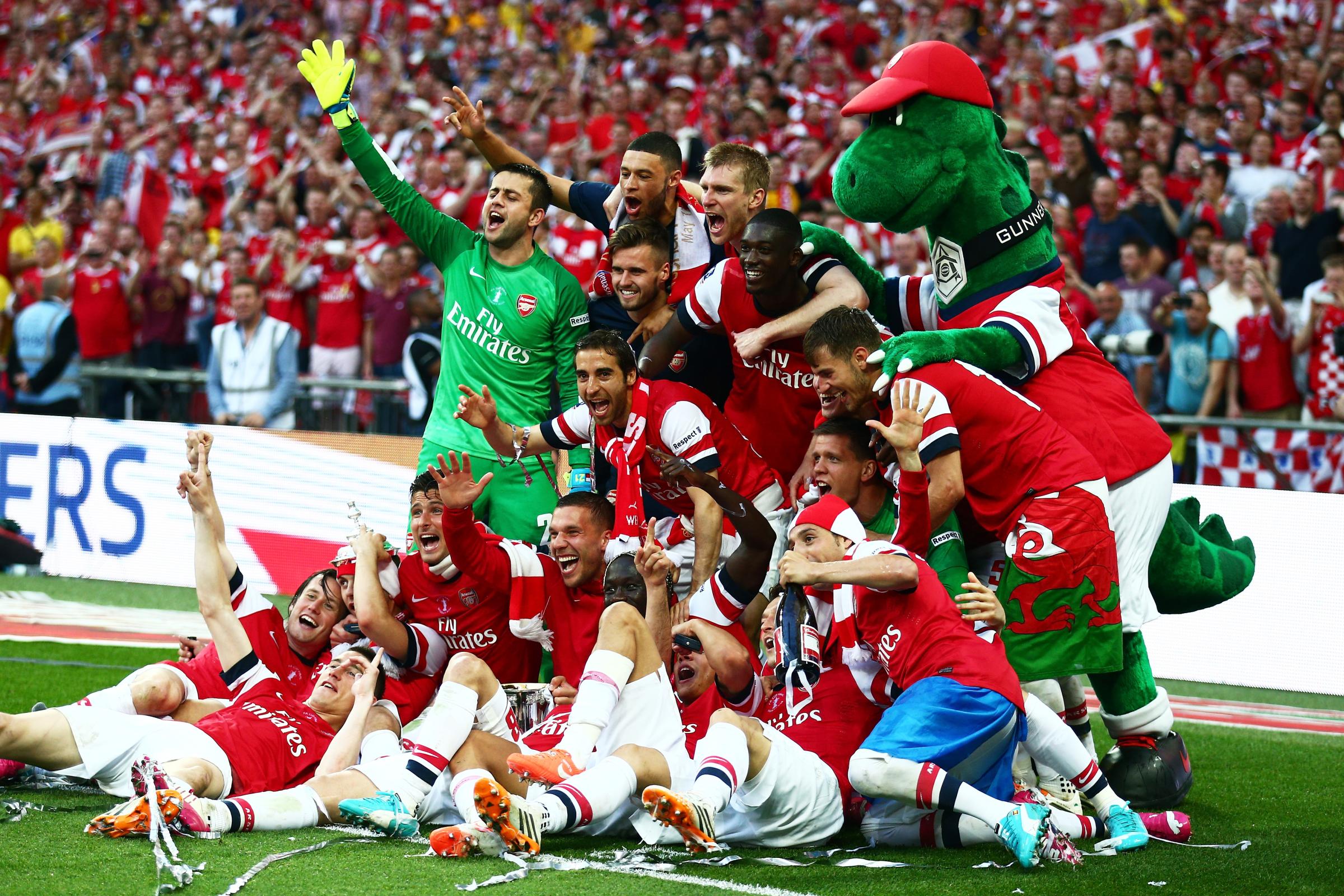 Arsenal players celebrate victory with mascot Gunnersauraus Rex after the FA Cup with Budweiser Final match between Arsenal and Hull City at Wembley Stadium on May 17, 2014 in London.