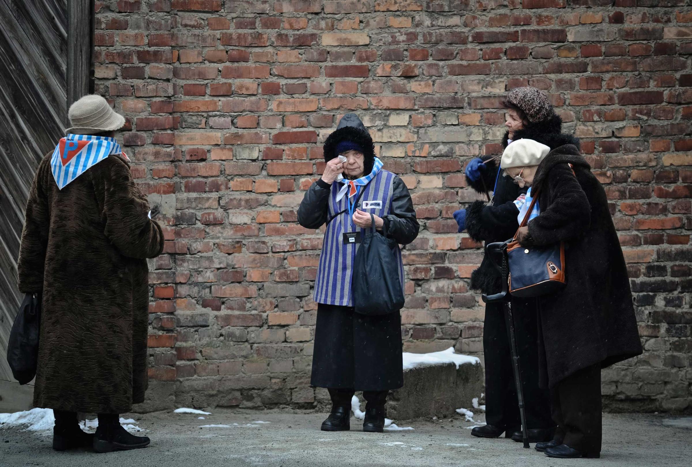 A Holocaust survivor wipes her eye while standing along with others outside a detention block of the Auschwitz Nazi death camp in Oswiecim, Jan. 27, 2015.