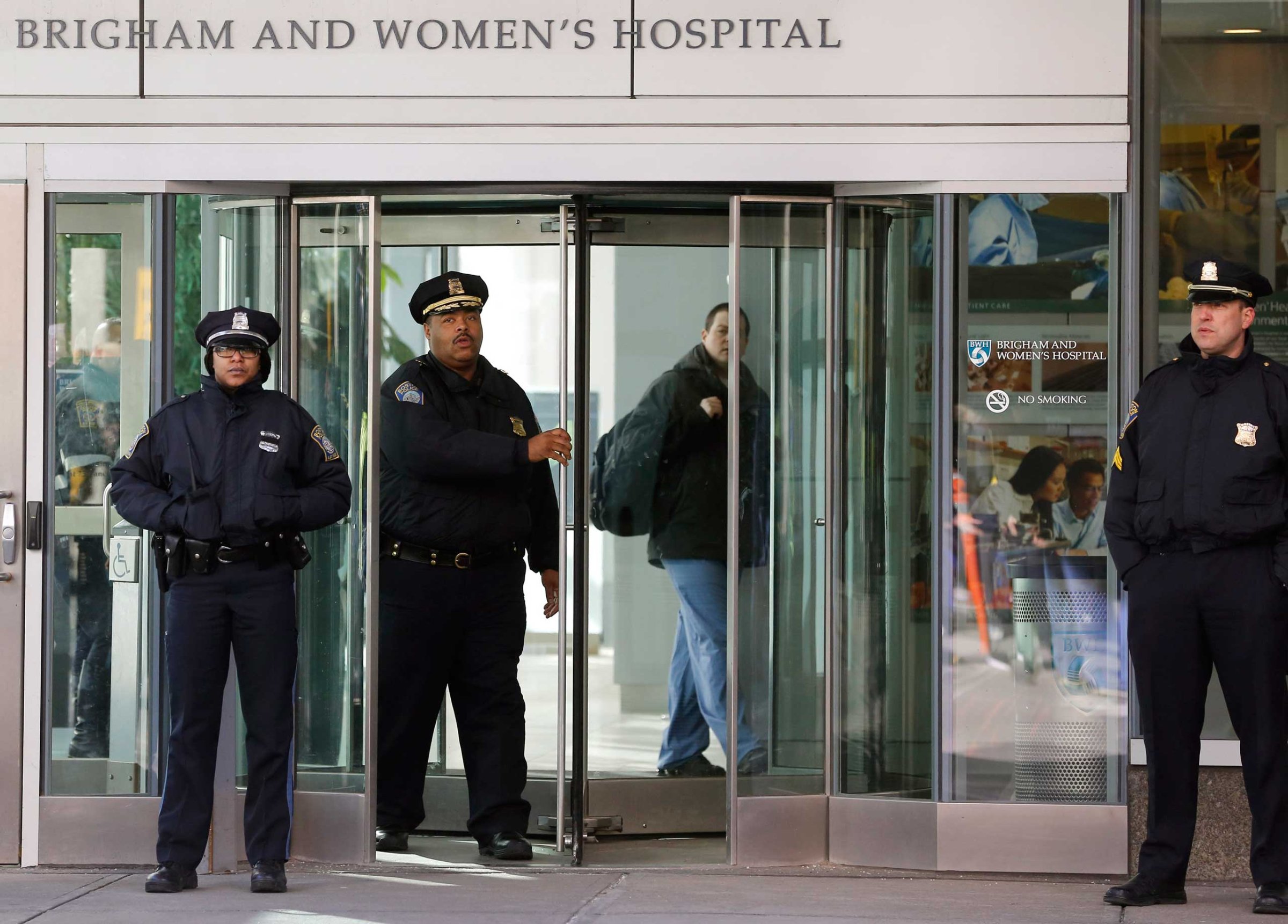 Boston Police Superintendent-in-Chief William Gross, center left, walks through a revolving door as he departs the Shapiro building at Brigham and Women's Hospital, Jan. 20, 2015 in Boston.