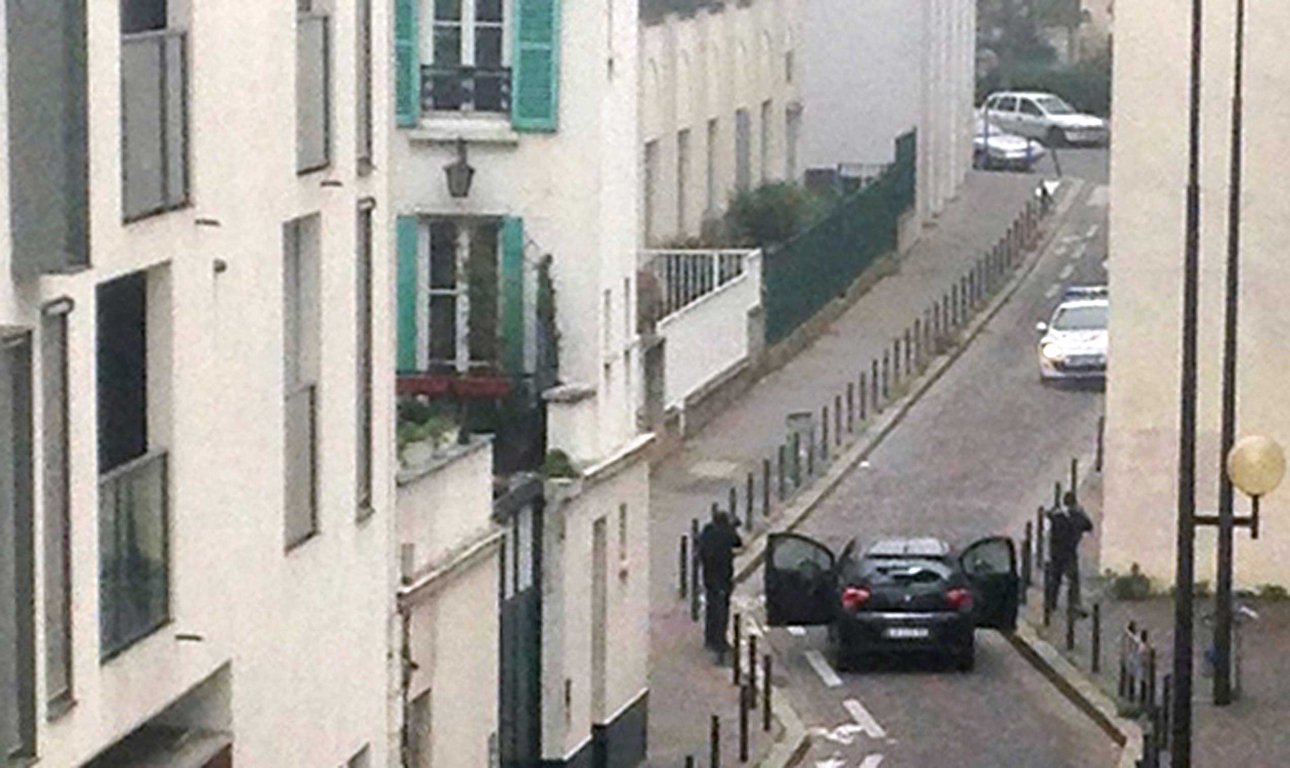 Armed gunmen face police officers near the offices of the French satirical newspaper Charlie Hebdo in Paris on Jan. 7, 2015.