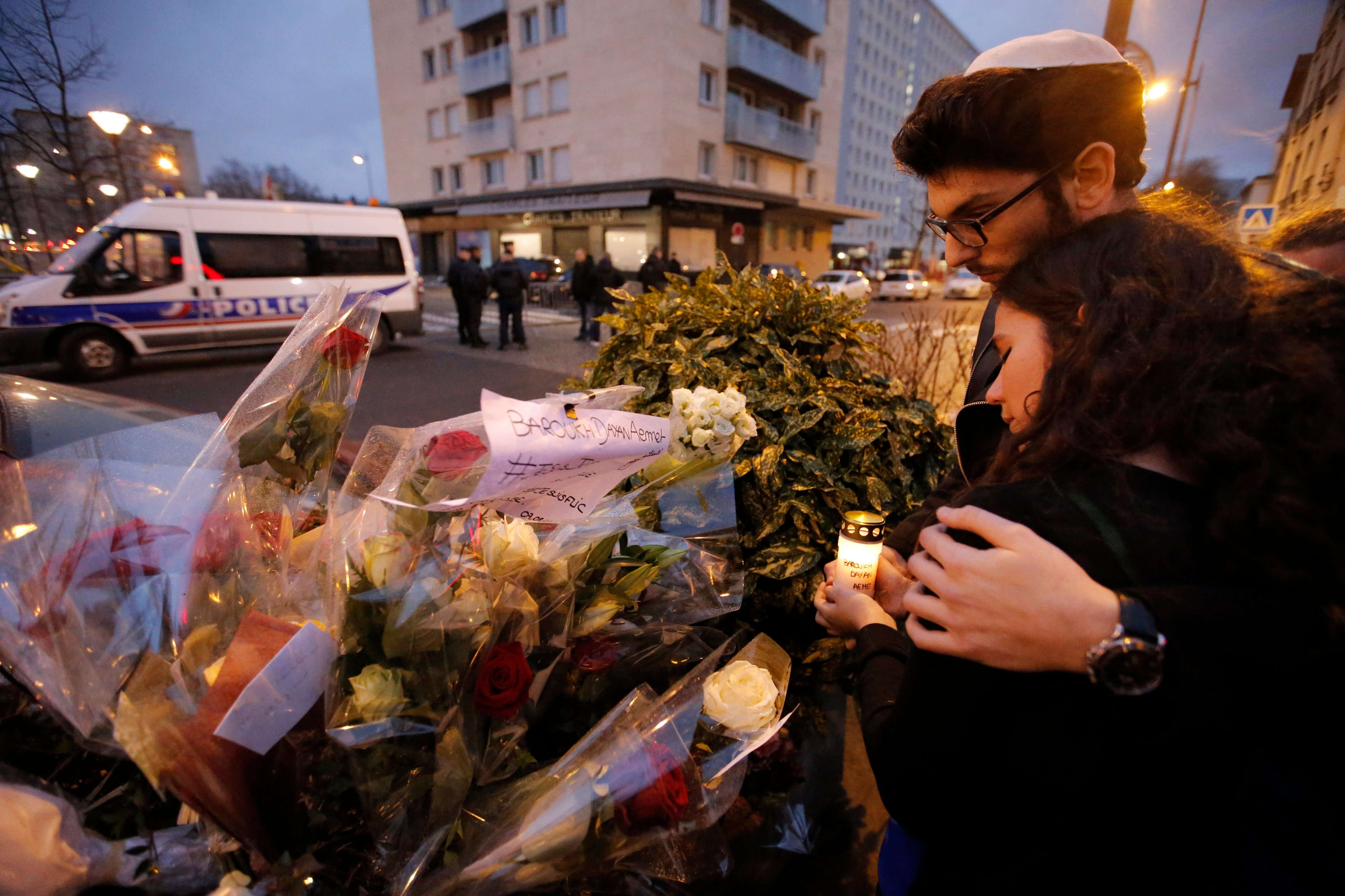 Esther Bekerman, 19, left, a cousin of one of the hostages, and Eliahou Rouas Cohen, 19, right, light a candle at a makeshift memorial near a kosher grocery store where four hostages were killed in Paris, Jan. 10, 2015. (Francois Mori—AP)