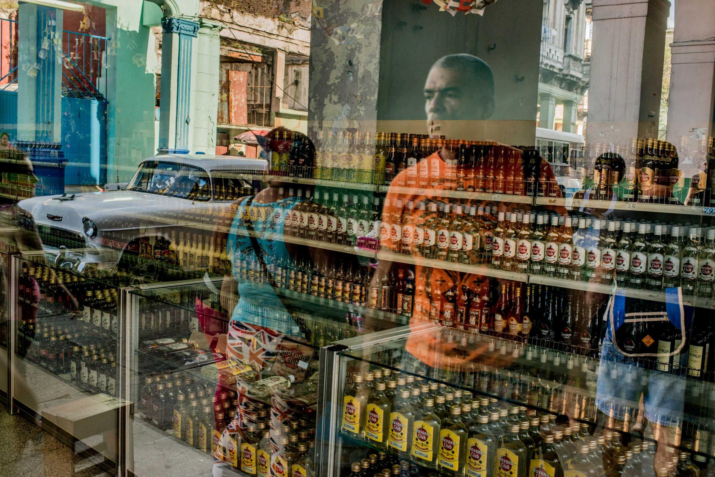 People outside a shop selling rum are reflected in the windows, in Havana, Dec. 22, 2014.
