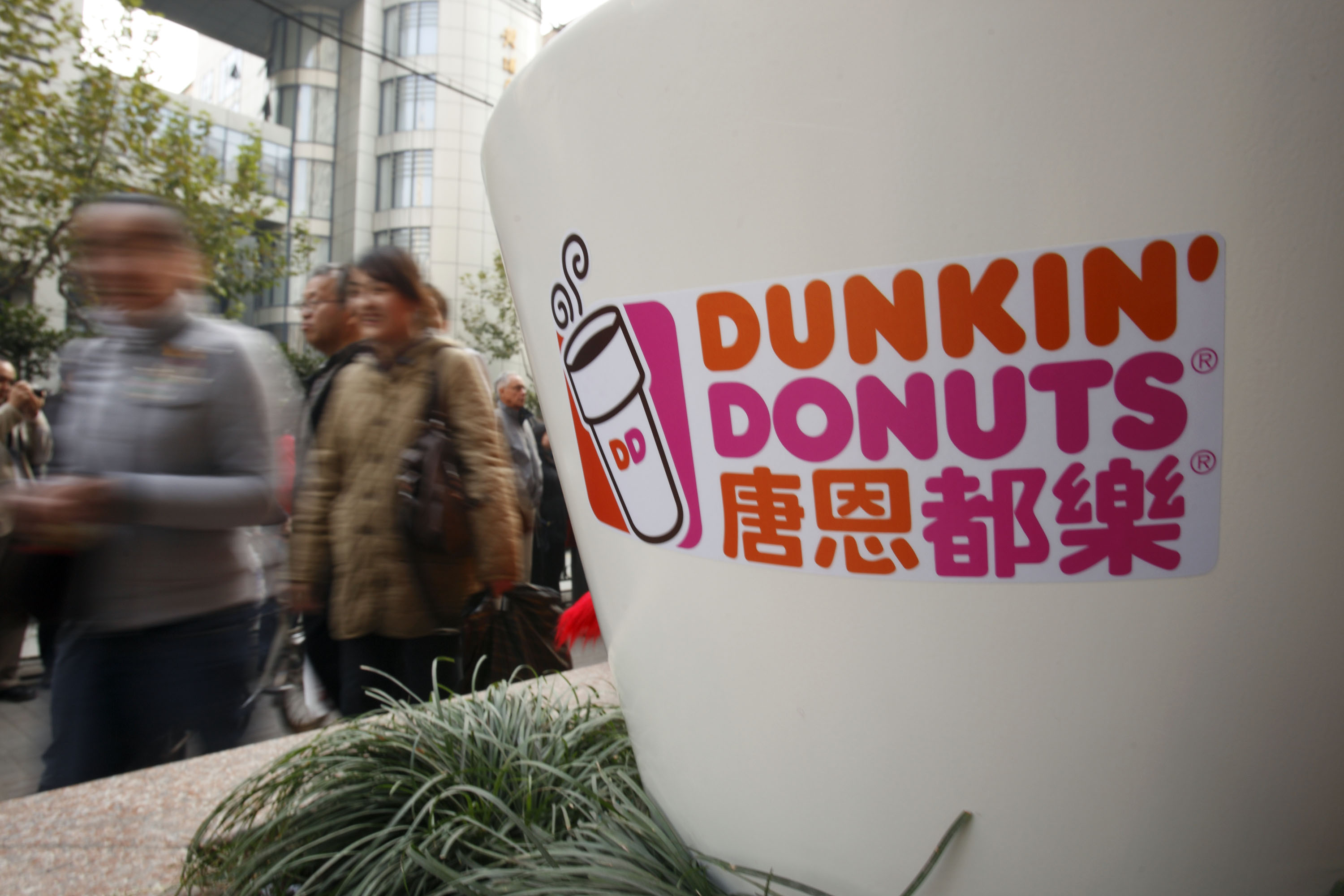 Pedestrians walk past the Dunkin' Donuts logo at the opening ceremony of the company's flagship store in Shanghai, China, on Nov. 20, 2008. (Bloomberg via Getty Images)