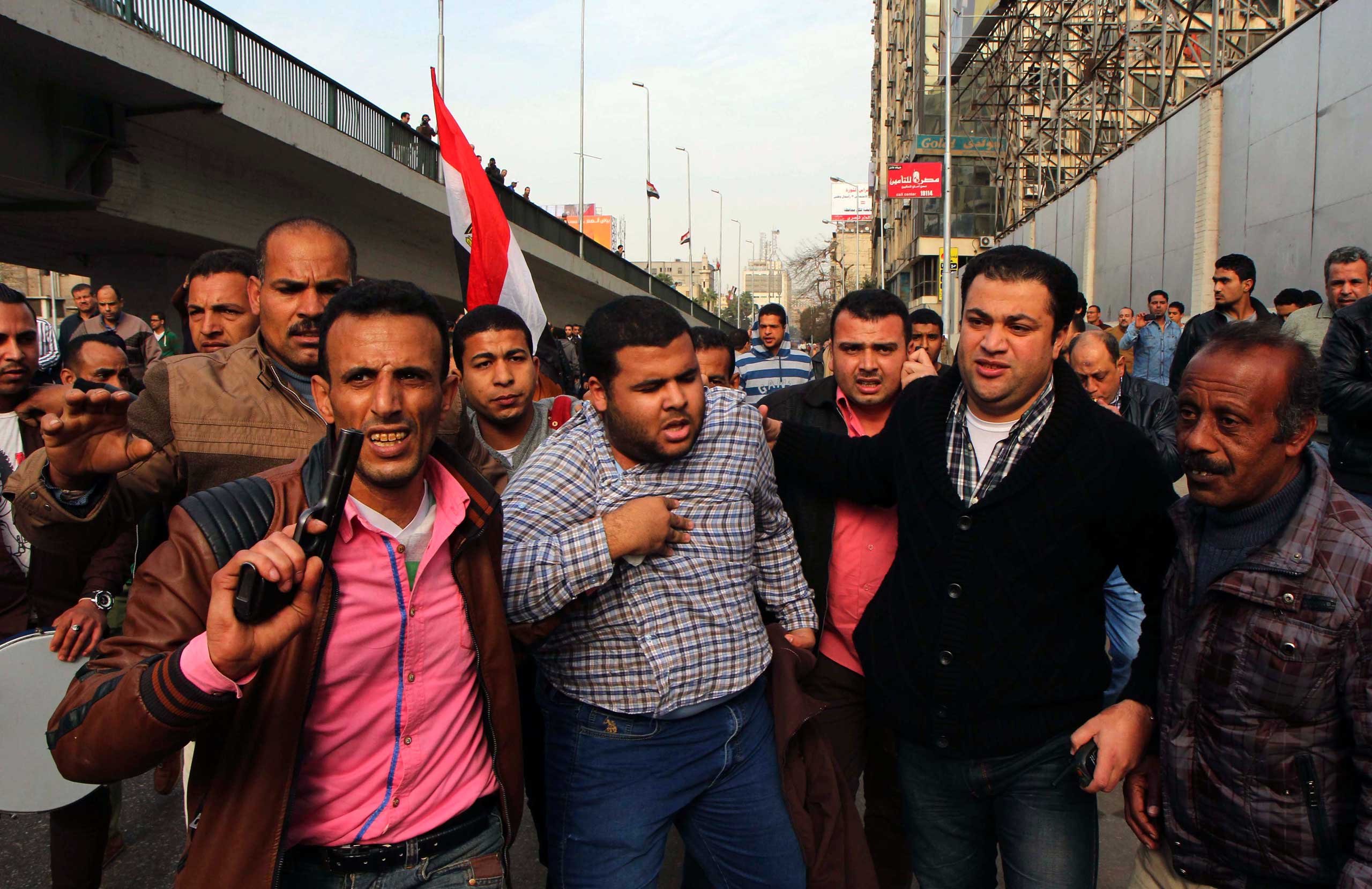 Man holds his chest as he is arrested by plainclothes police in downtown Cairo, Jan. 25, 2015.