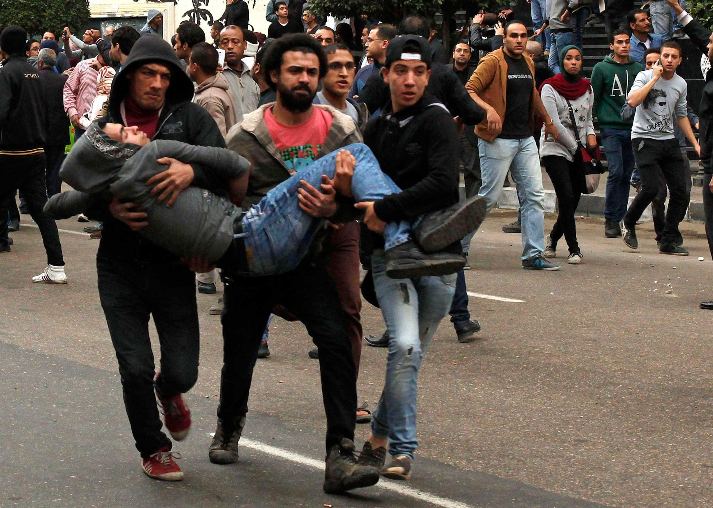 Anti-government protesters help an injured protester when pro-government protesters threw stones during a protest in front of the press syndicate in Cairo, Jan. 25, 2015.