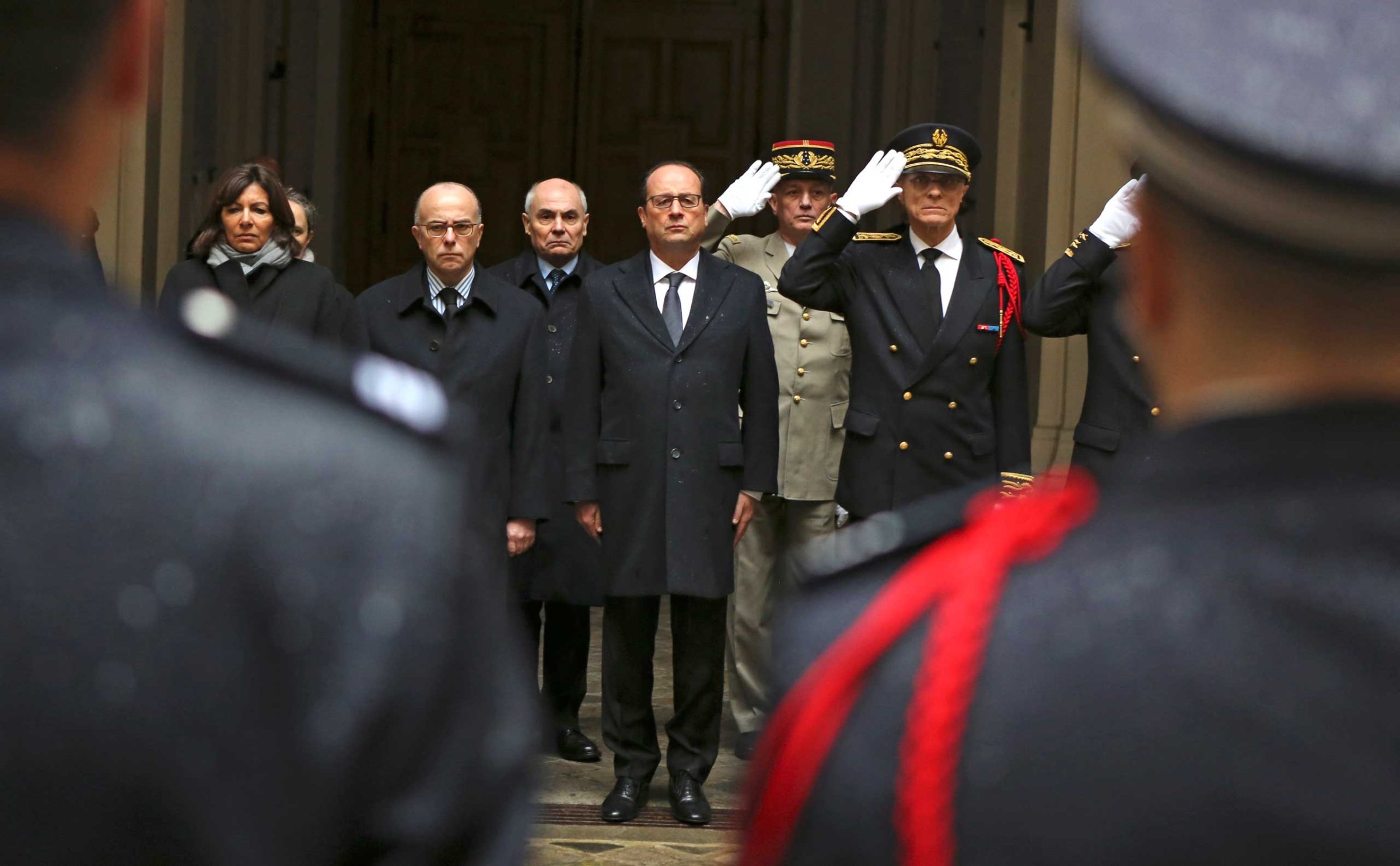 French President Francois Hollande, center, with at his side interior minister Bernard Cazeneuve, left, and Paris police prefect Bernard Boucault, right, stands for a minute of silence, at Paris Prefecture in Paris, Jan. 8, 2015.