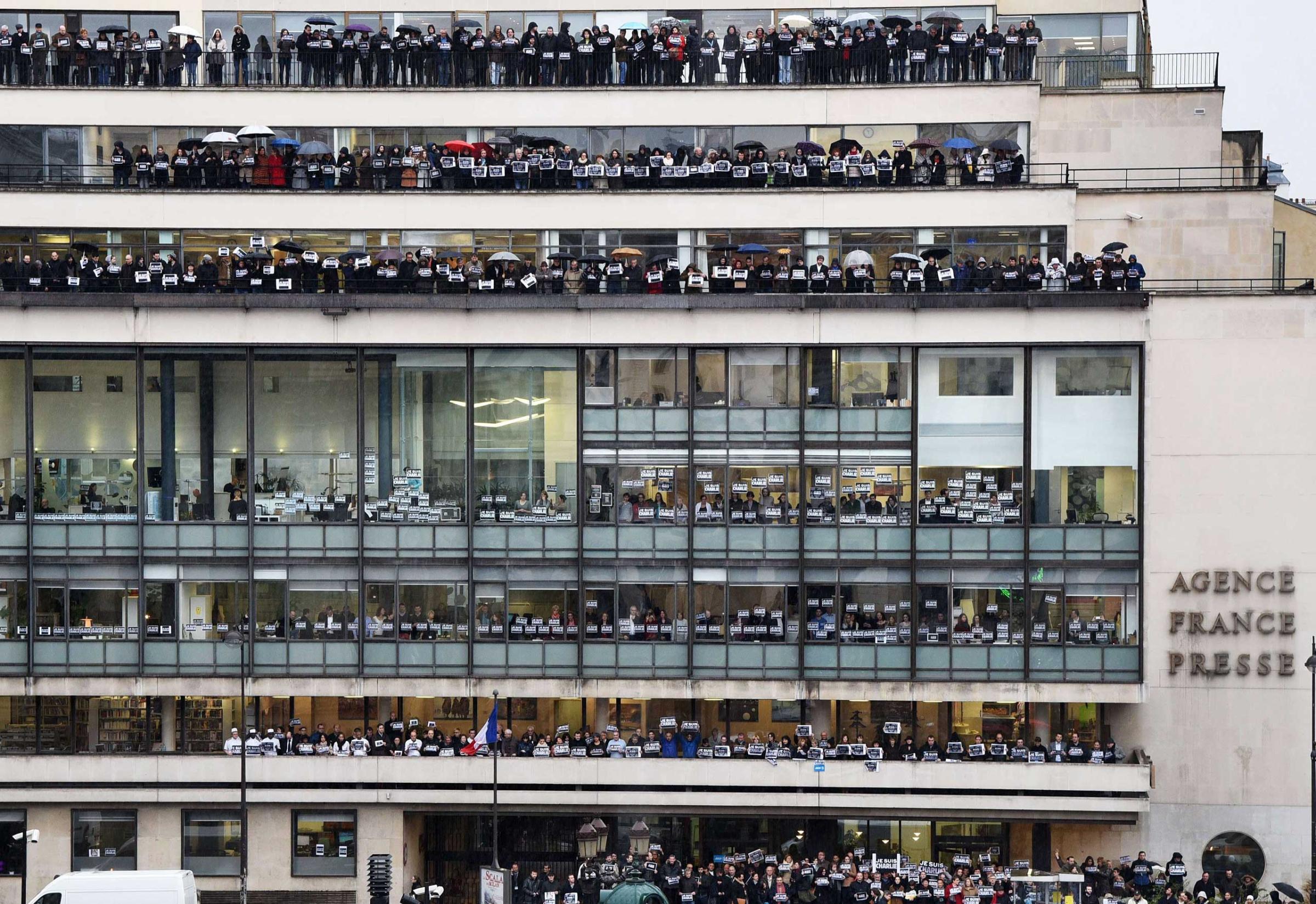 Journalists of international press agency Agence France-Presse hold signs reading "Je suis Charlie" (I am Charlie) at their headquarters in Paris as they observe a minute of silence on Jan. 8, 2015.
